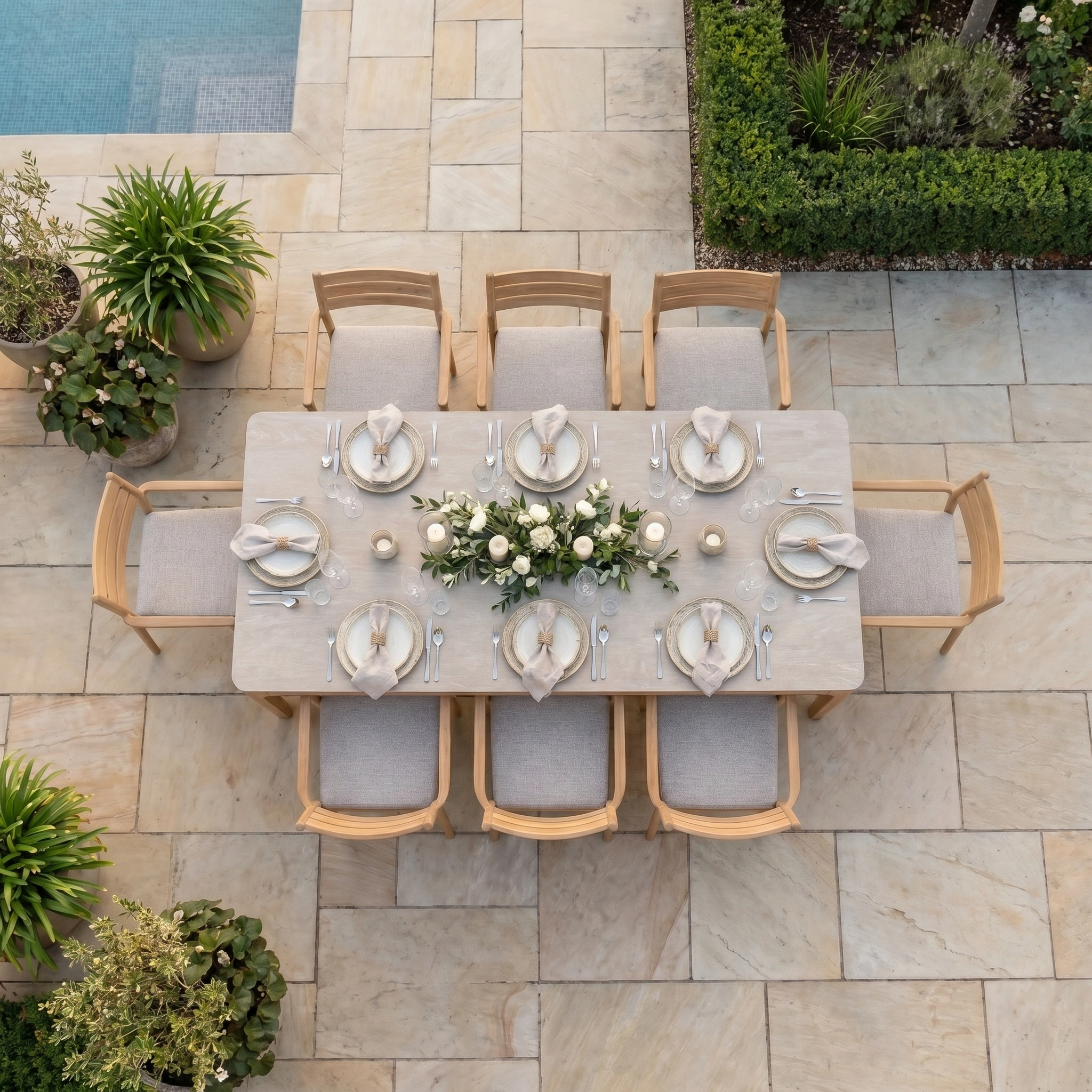 Aerial view of the Siena 8 Seat Dining Set with Ceramic Top Table in Fawn beside a pool, the table artfully adorned with flowers and candles for stylish outdoor dining.