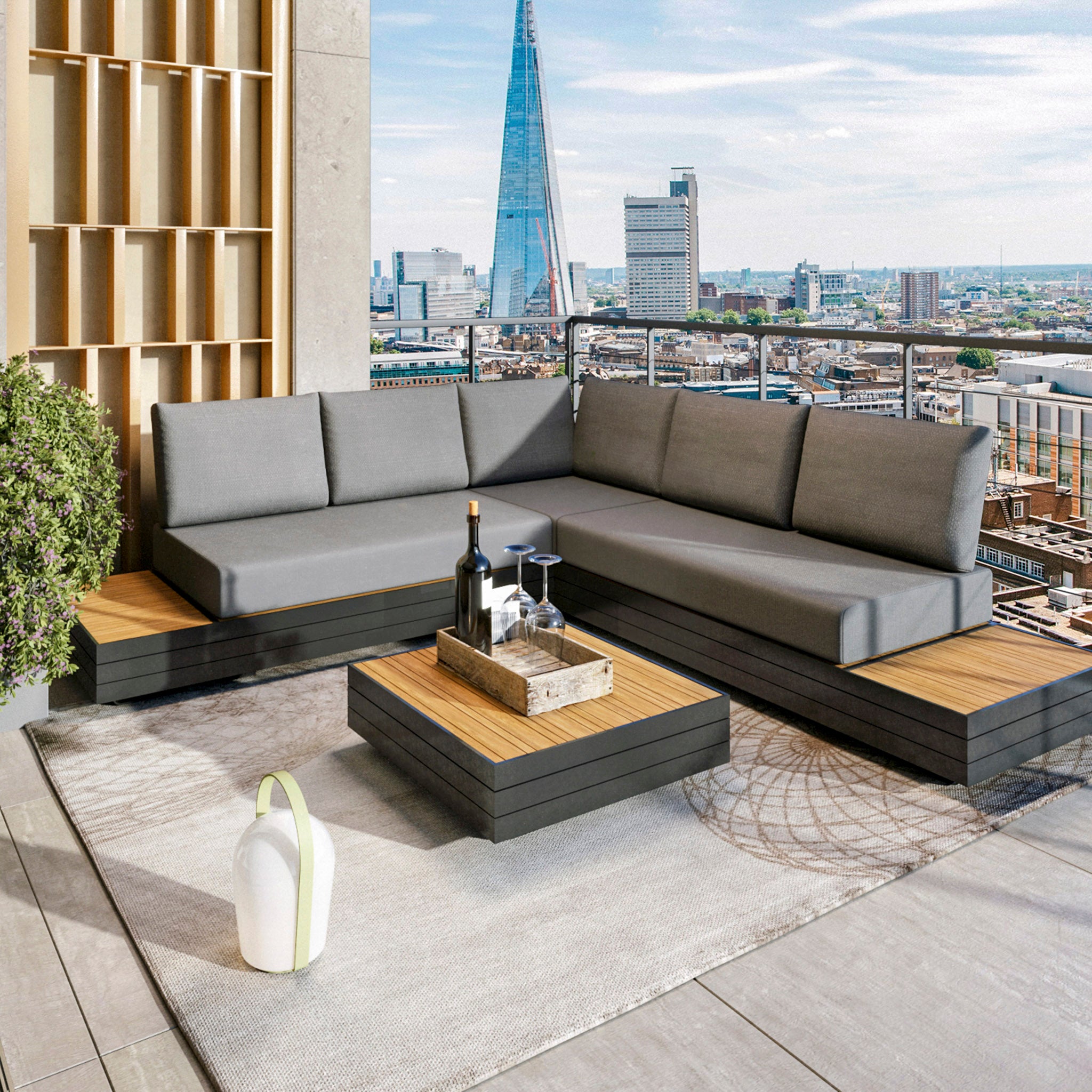 Modern rooftop patio featuring the Panama Luxury Outdoor Corner Group Set in Washed Grey and a low wooden table crafted from sustainable teak, accented with wine glasses and a candle, all set against a stunning city skyline.