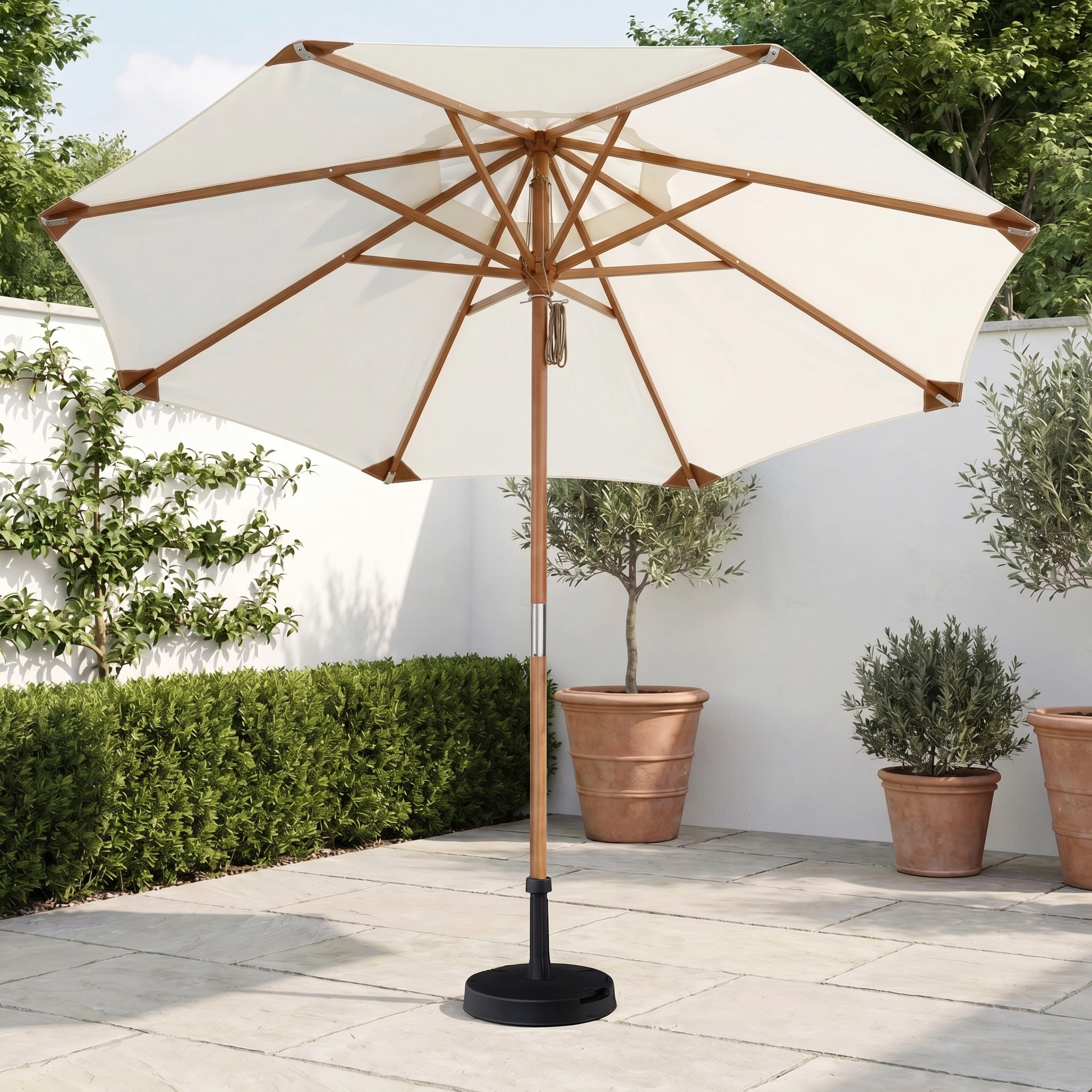 The Styx 3m Round Deluxe Wooden Parasol in Beige stands on a stone terrace, surrounded by potted plants and greenery.