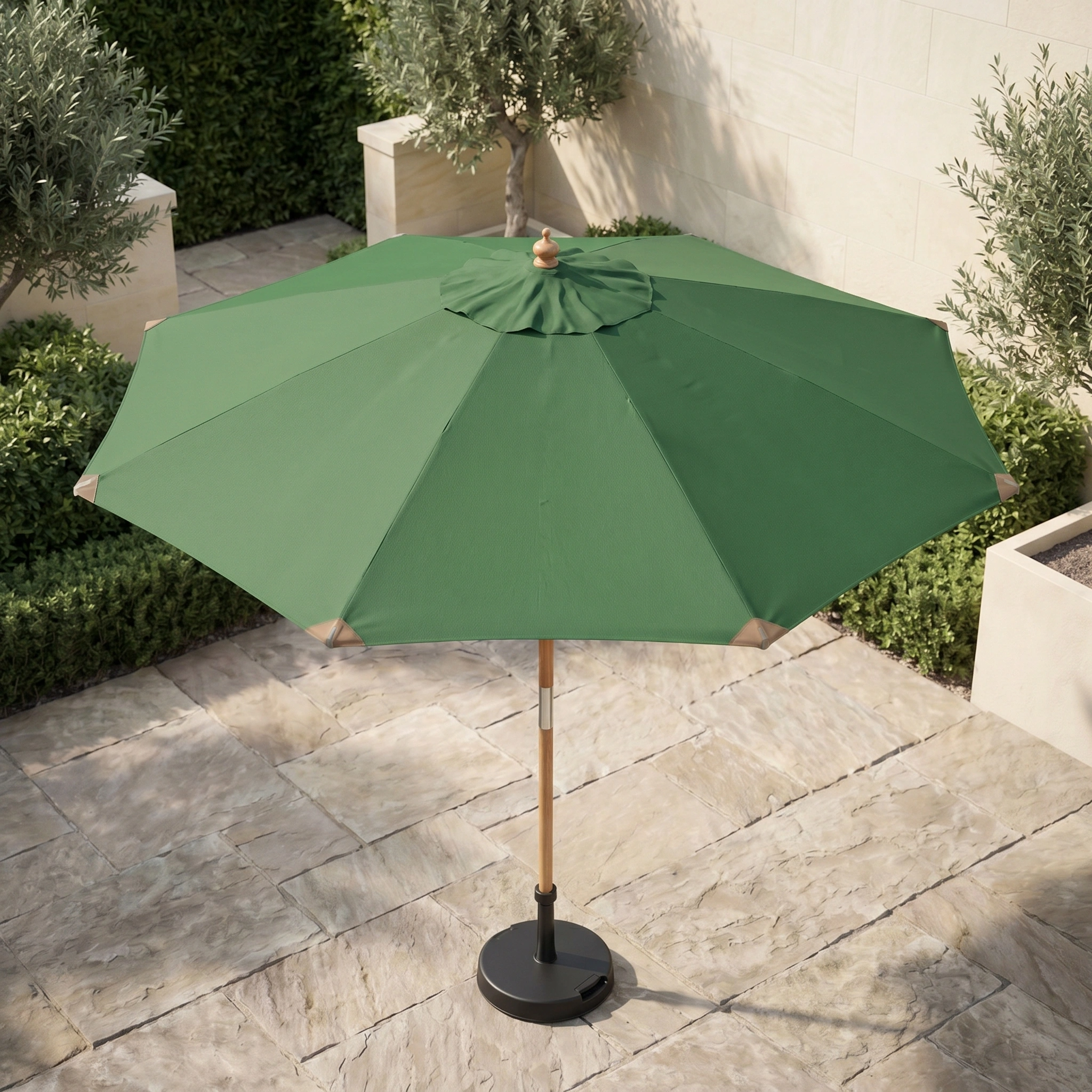 The Styx 3m Round Deluxe Wooden Parasol in Green stands on a stone-tiled terrace, surrounded by plants and bordered by a cream-colored wall.