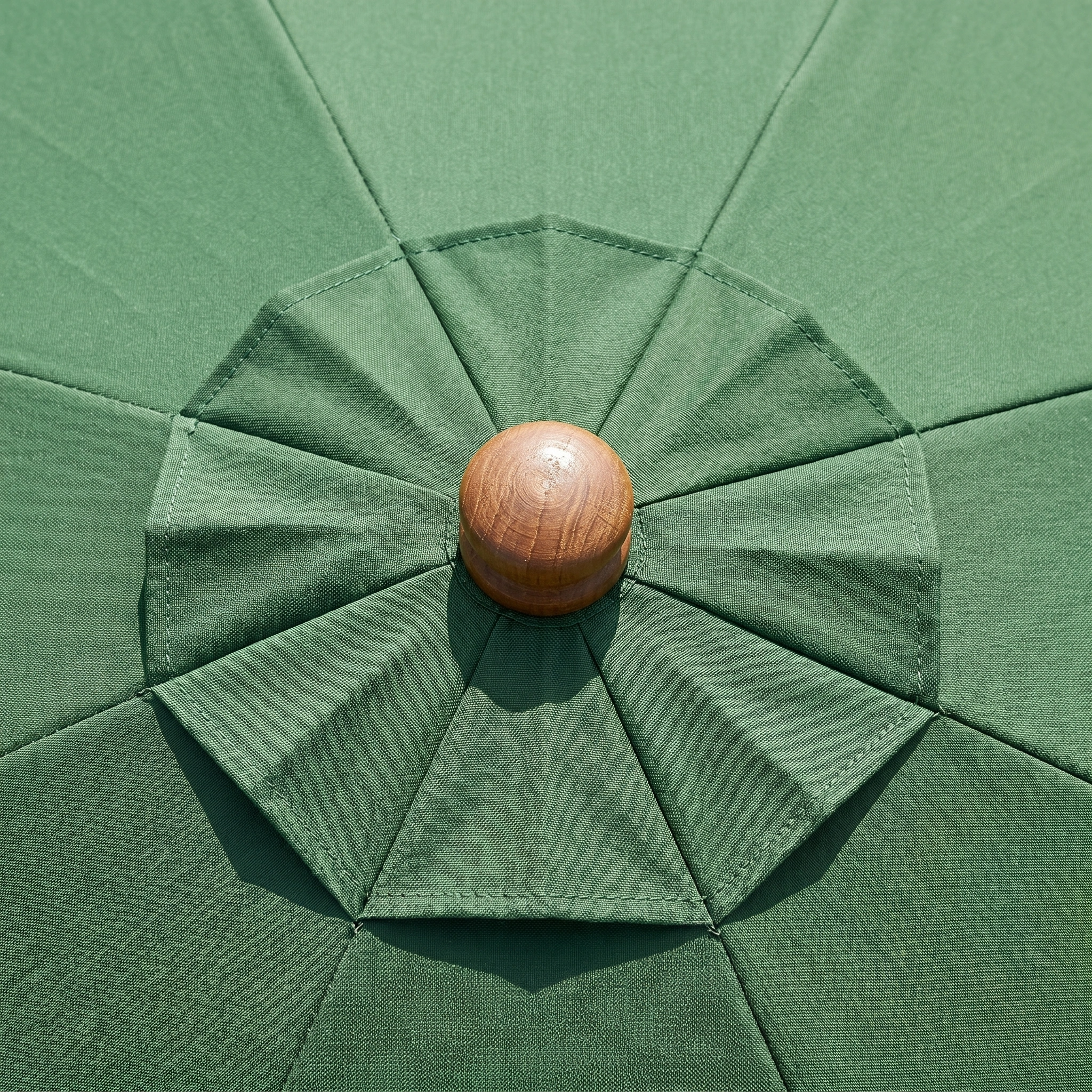 Close-up of the Styx 3m Round Deluxe Wooden Parasol in Green, highlighting its elegant wooden finial and detailed craftsmanship at the top.