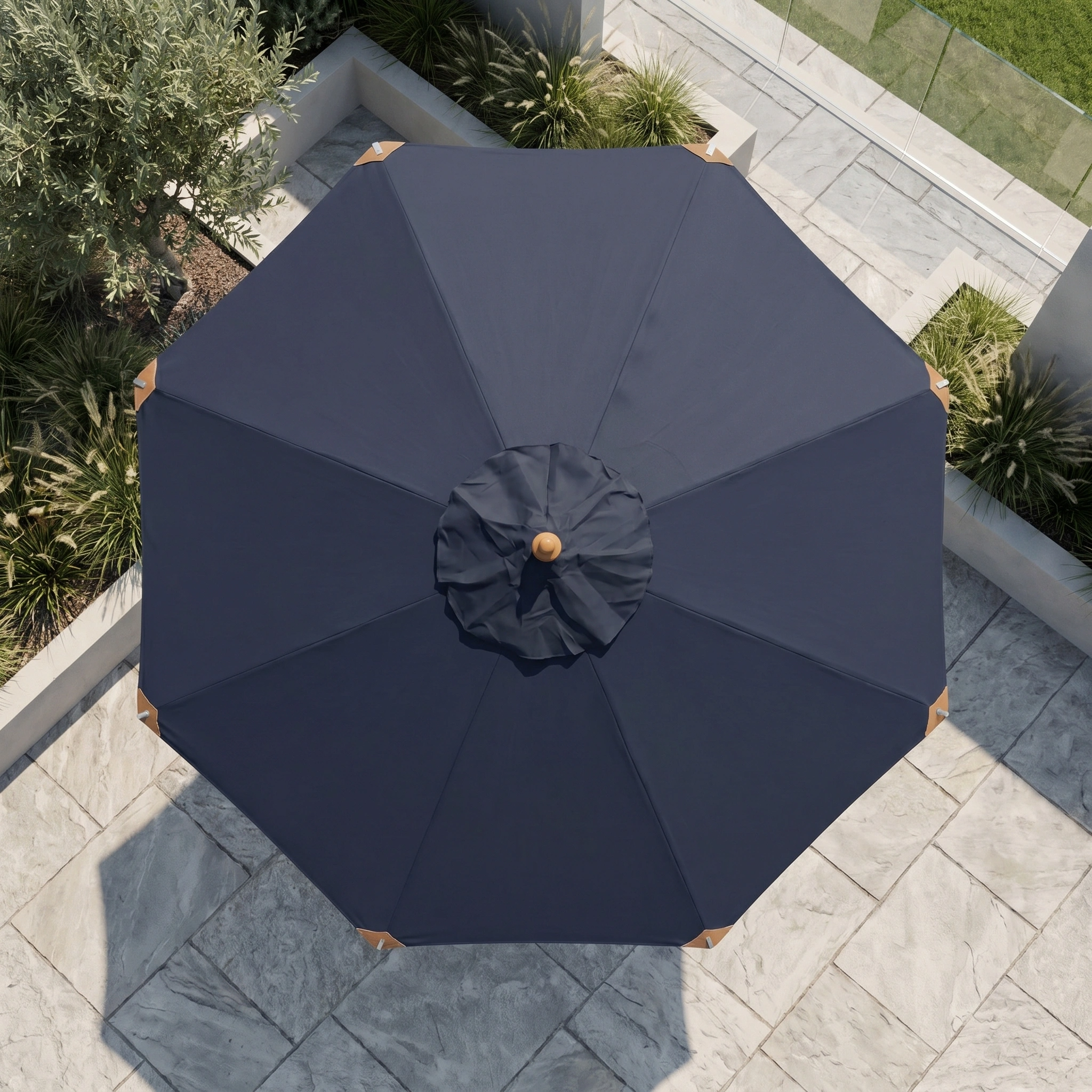 Top-down view of the Styx 3m Round Deluxe Wooden Parasol in Navy on a stone-tiled outdoor area with greenery nearby.