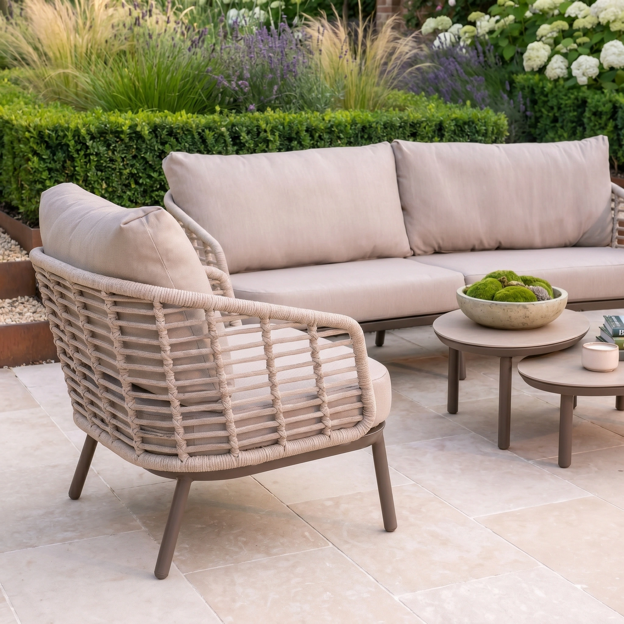 The Sutera 3 Seat Sofa Set in Putty features all-weather cushions, a chair, and tables—offering a modern, stylish garden furniture arrangement perfect for relaxing outdoors.
