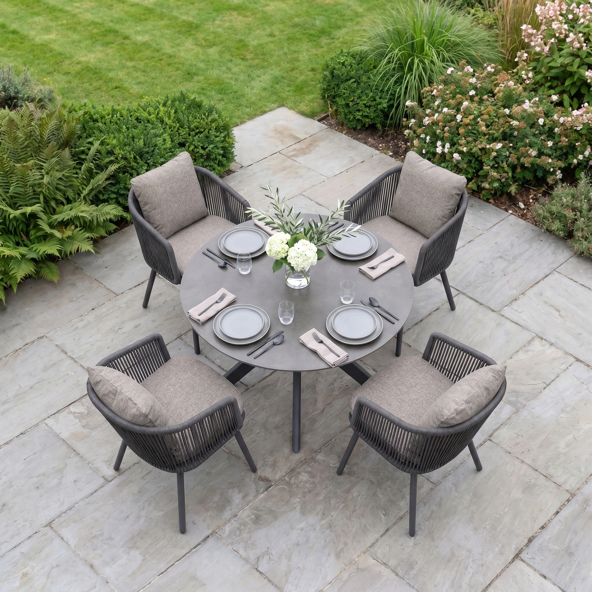 The Theia 4 Seat Round Rope Dining Set with Albatross Table in Truffle features four cushioned chairs and a stylish round table, providing an elegant outdoor dining setup for your garden or patio.