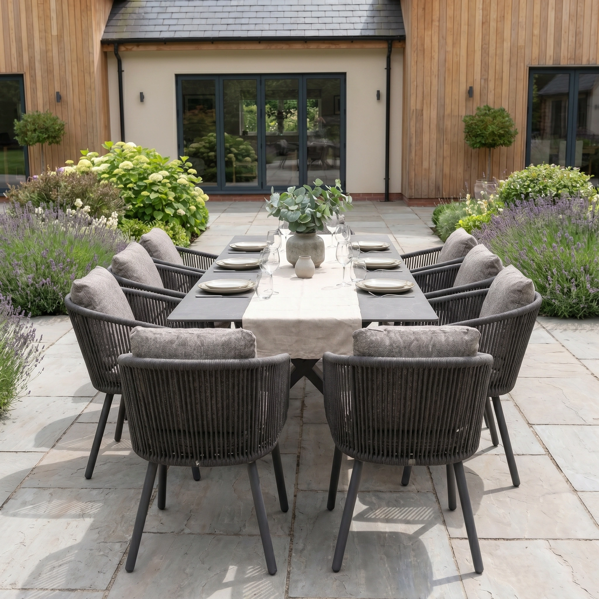 Theia 8 Seat Rope Dining Set with Albatross Extending Table in Truffle features stylish gray chairs and a centerpiece, making it perfect for modern outdoor patio gatherings.