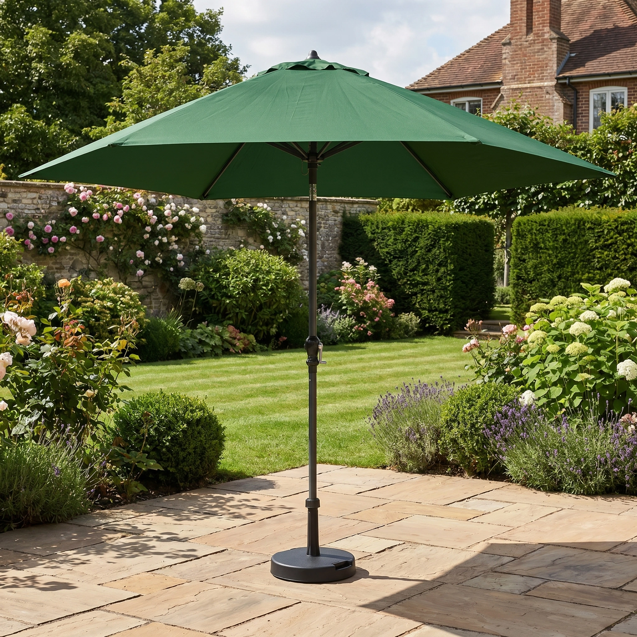 The Triton 2.5m Round Aluminium Parasol in Green stands on a stone patio among pink roses and lush greenery, offering stylish shade and UV protection in your garden.