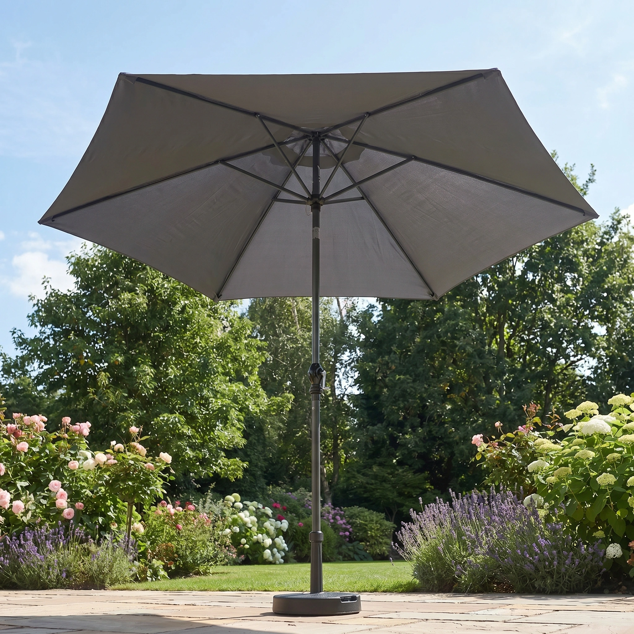The Triton 2.5m Round Aluminium Parasol in Grey provides stylish shade and UV protection for your outdoor space, perfect for stone terraces surrounded by blooming flowers and lush garden plants.