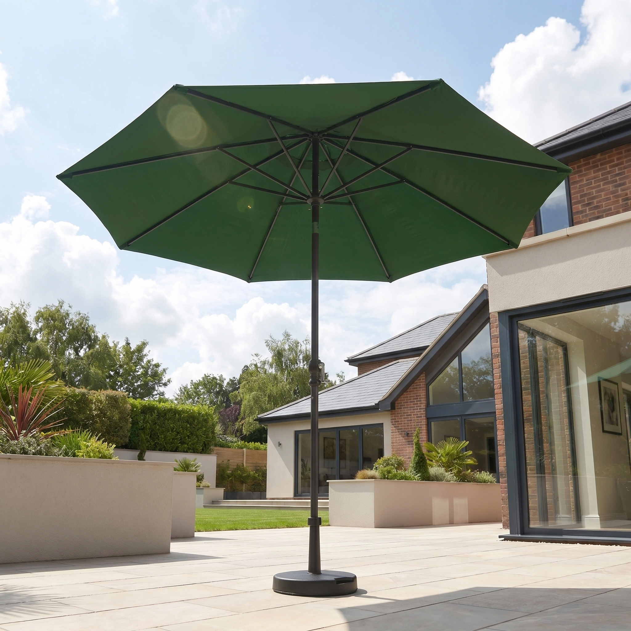 The Triton 3m Round Aluminium Parasol in Green adds stylish shade and UV protection to your modern backyard terrace, complementing the house and garden in the background.