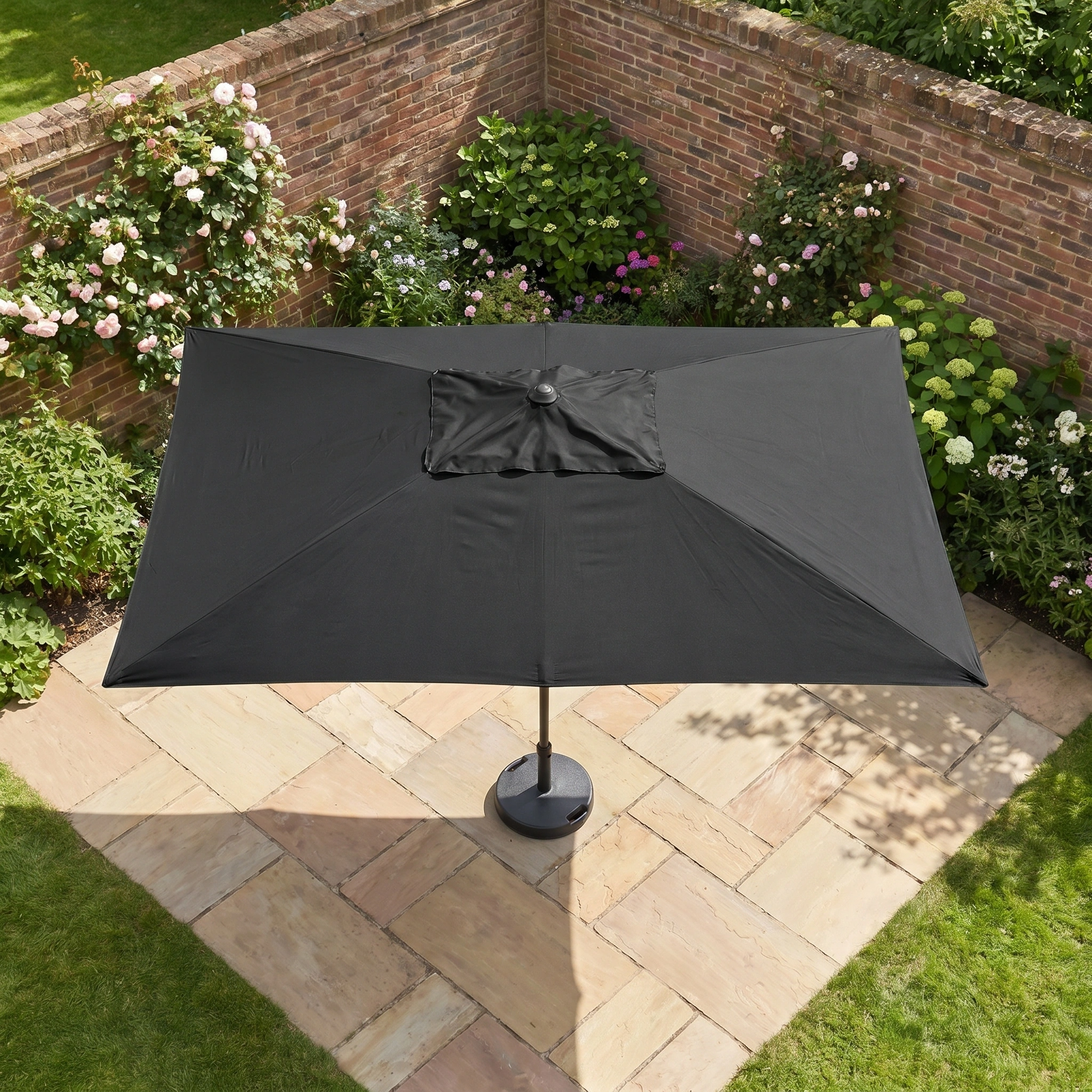 The Triton 3m x 2m Rectangular Aluminium Parasol in Black provides generous shade and UV protection, perfect for relaxing on your garden terrace surrounded by brick walls and blooming plants.