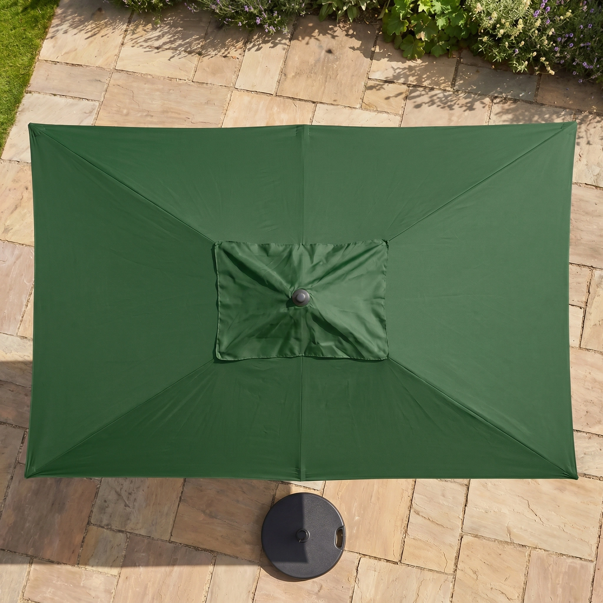 The Triton 3m x 2m Rectangular Aluminium Parasol in Green offers shade and style for your outdoor space, perfect for patios with stone tiles and surrounding plants.