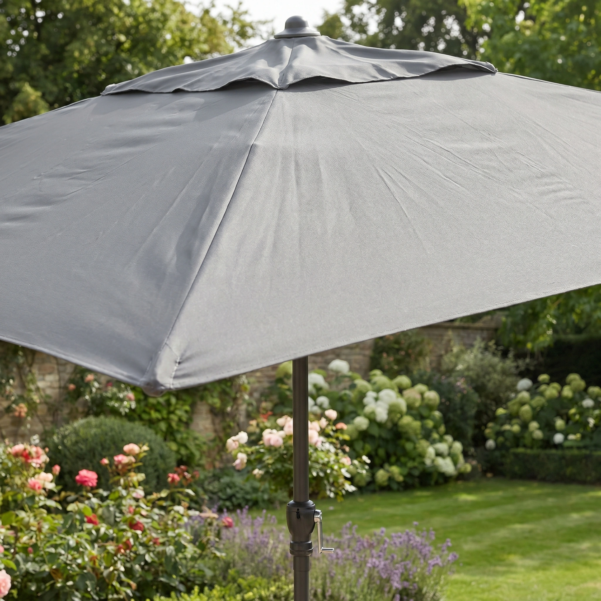 The Triton 3m x 2m Rectangular Aluminium Parasol in Grey is the ideal UV sun protector for your outdoor space, shading gardens filled with green plants and colorful flowers.