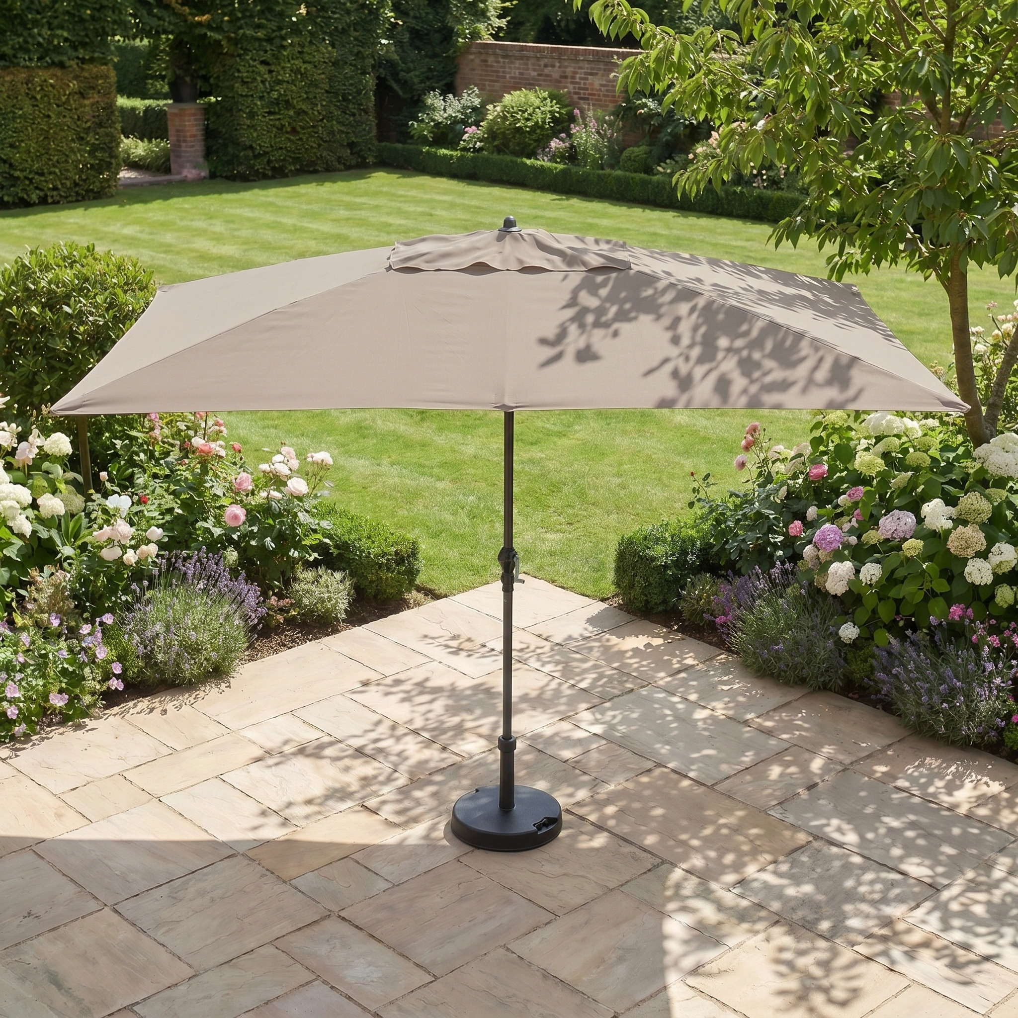 The Triton 3m x 2m Rectangular Aluminium Parasol in Khaki, shown on a tiled patio among garden plants and green lawn, is fade resistant and provides reliable UV protection for comfortable outdoor relaxation.