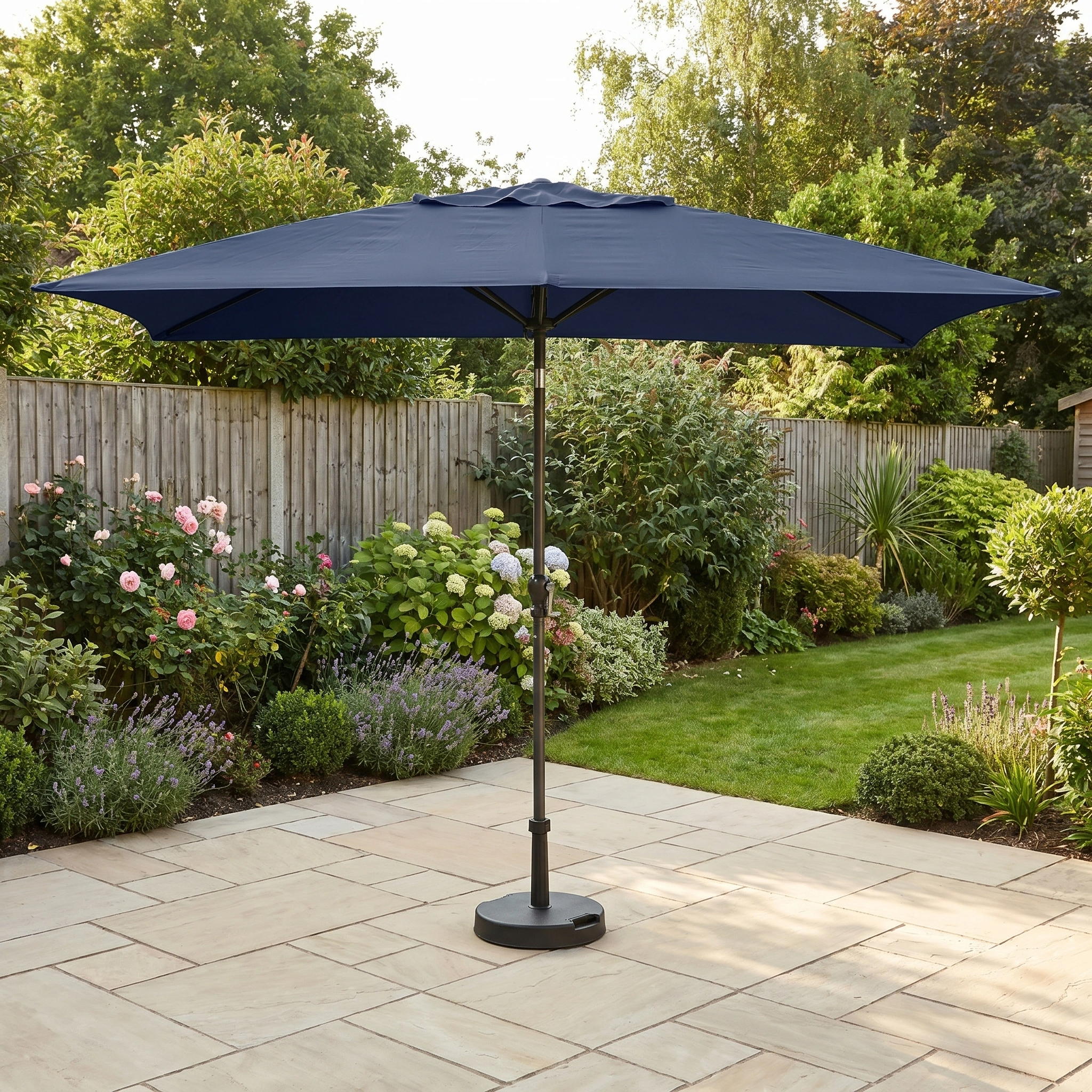 The Triton 3m x 2m Rectangular Aluminium Parasol in Navy with UV protection stands on a paved patio in a garden.