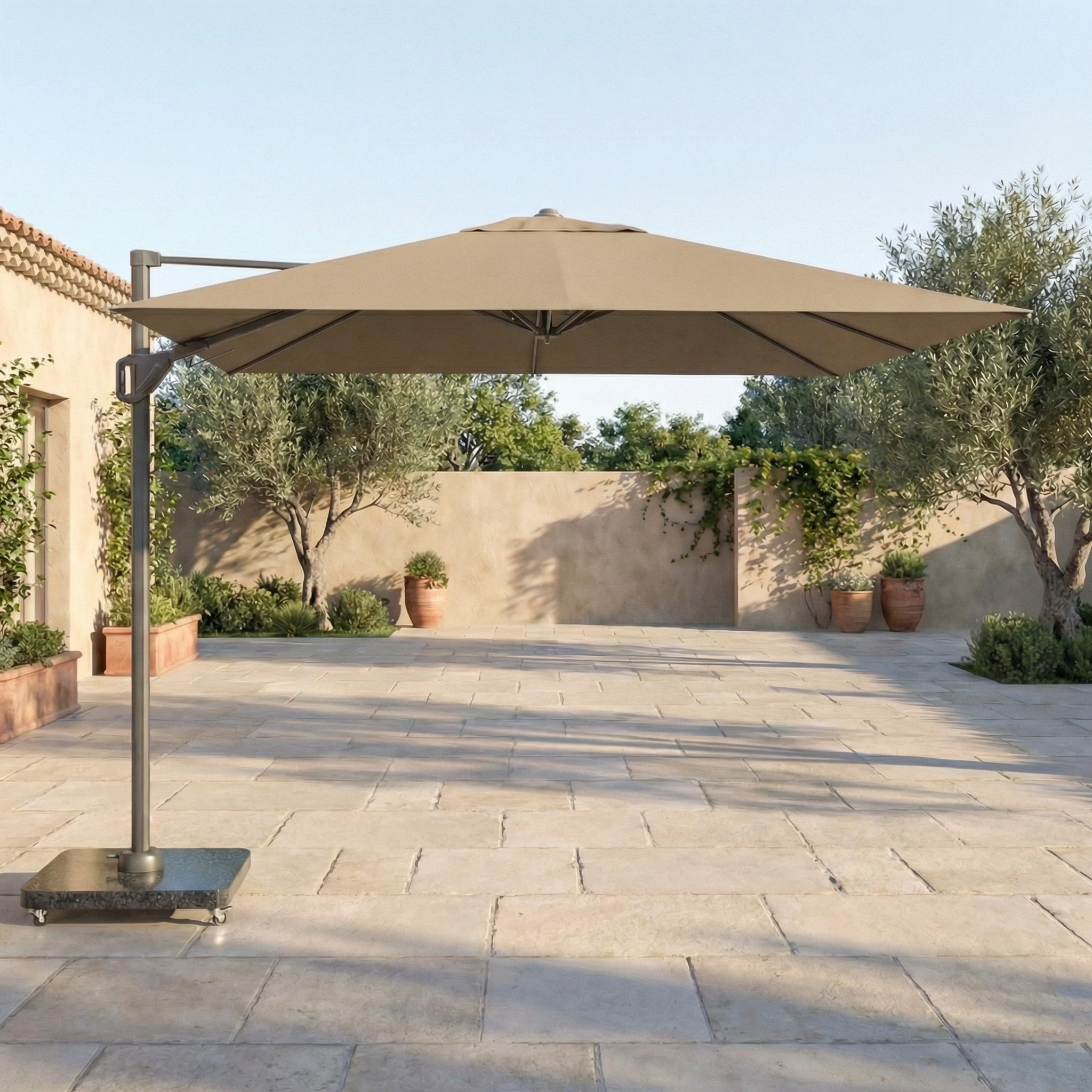 The Voyager T1 3m x 2m Rectangular Cantilever Parasol in Taupe with a 90kg Granite Base shades a tiled courtyard, with potted plants and trees in the background.