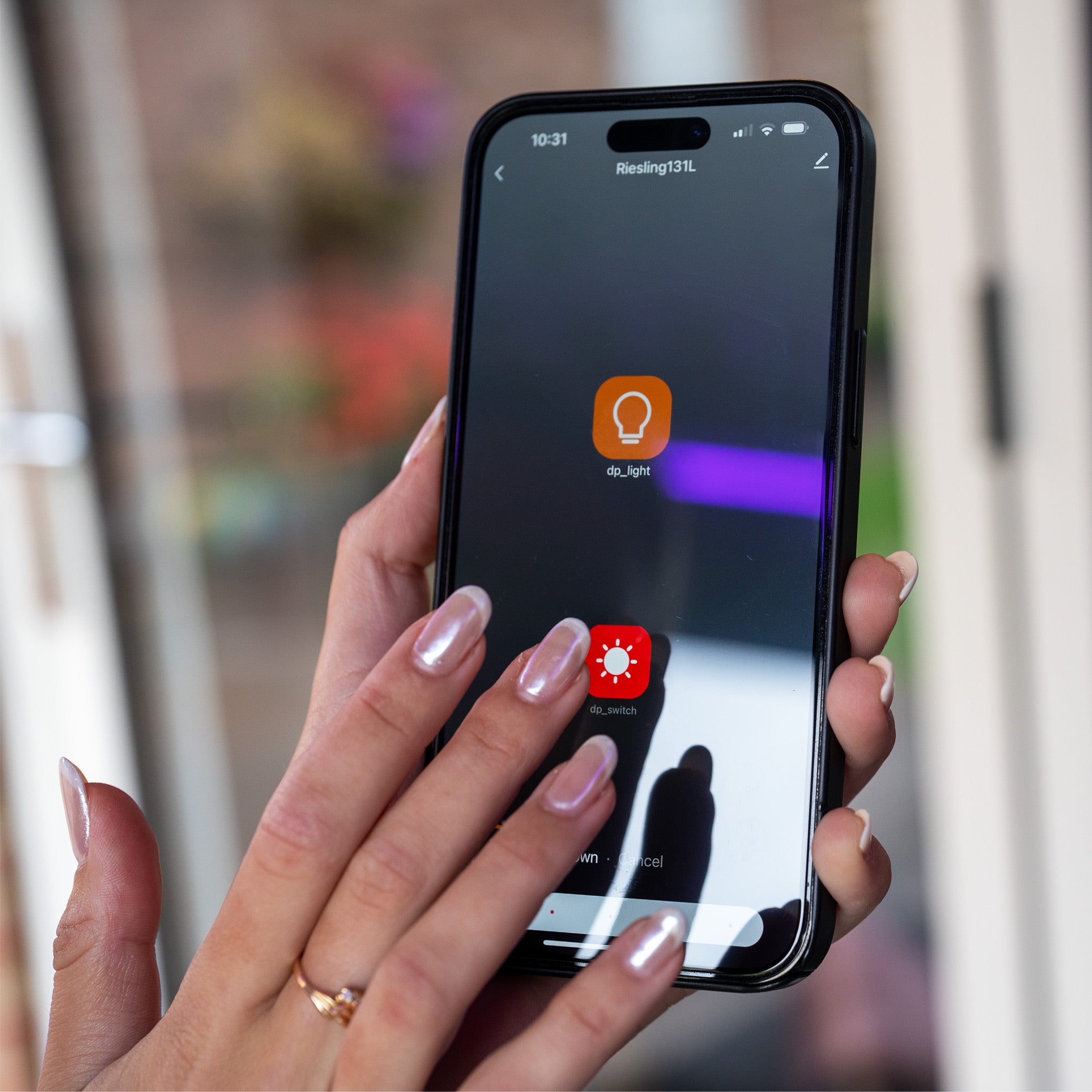A person holds a smartphone showing a lighting control app with two icons, ideal for creating ambiance under the PergoSTET Plus 3m x 4m Wall Mounted Pergola with LED Lighting and 3 Drop Sides in Grey.