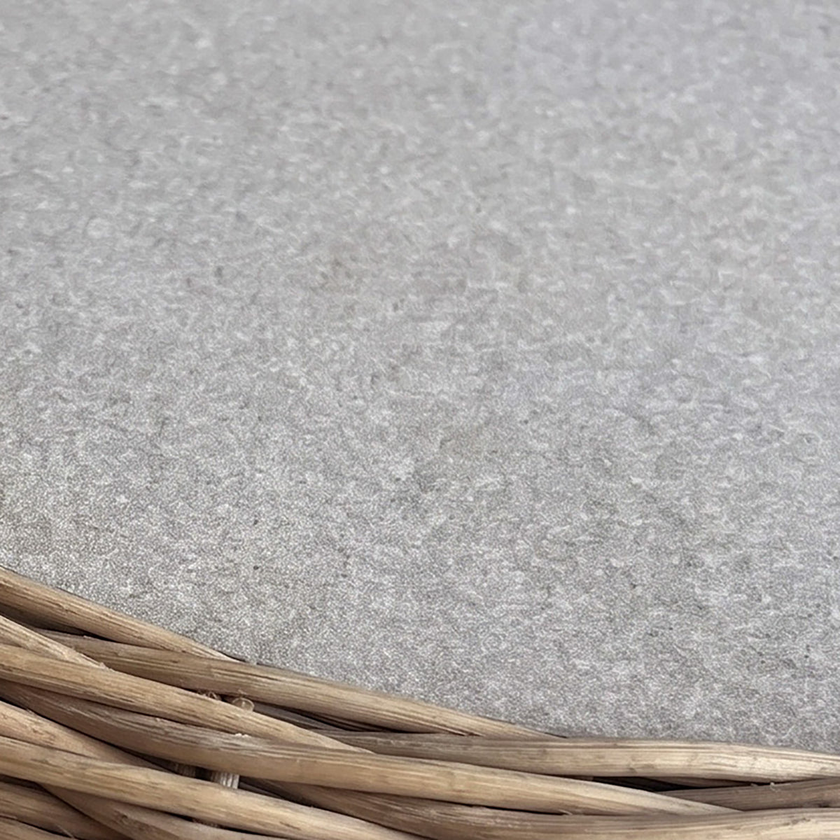 Close-up of woven wicker basket edge on a light gray textured surface, mirroring the refined craftsmanship seen in the Vela 6 Seat Rectangular Dining Set in Wheat.