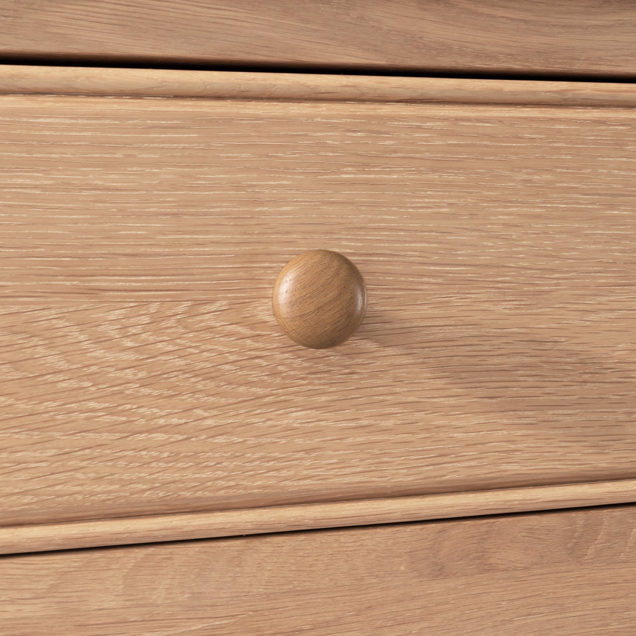 Close-up of a wooden drawer with a round knob, highlighting the natural wood grain—an ideal match for the Amberley Large Bookcase in Light Oak.