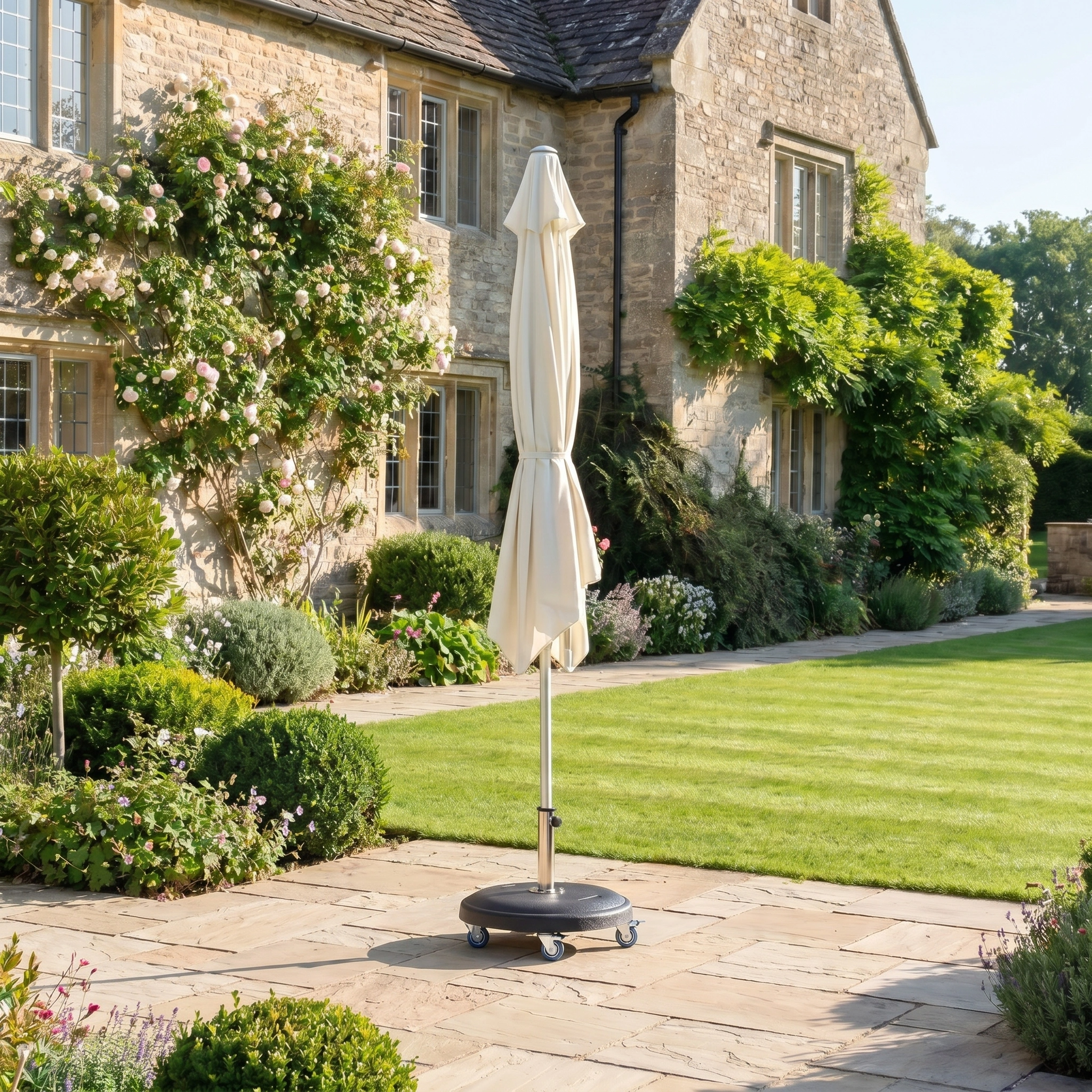 The Zelos 2.5M Round Parasol with LED Lighting in Cream stands on a stone terrace beside a stone house, providing stylish sun protection for your sunny garden when open.
