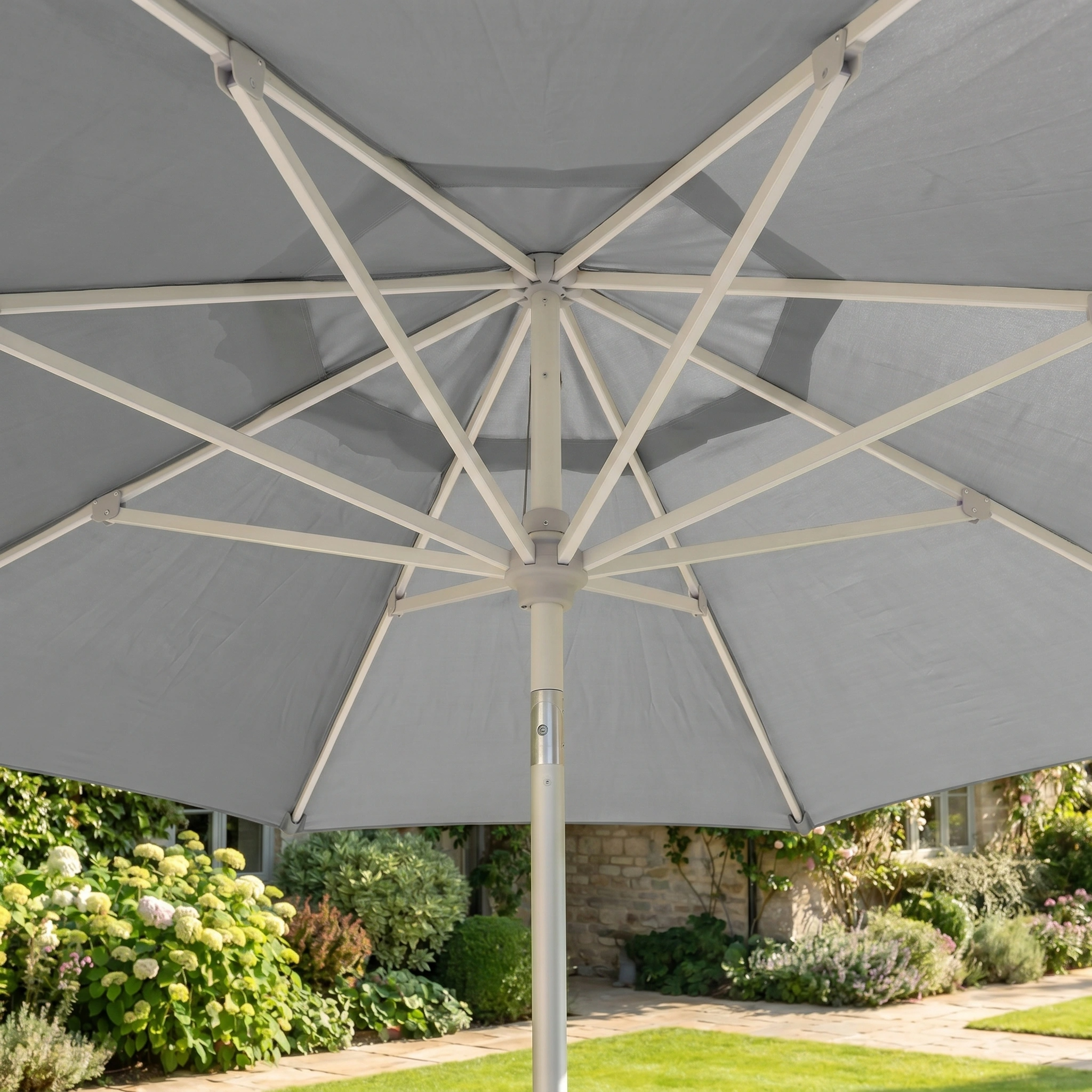 Enjoy the view from beneath the Zelos 2.5M Round Parasol with LED Lighting in Grey, surrounded by garden greenery. This stylish parasol provides reliable UV protection for relaxing, sunny days outdoors.