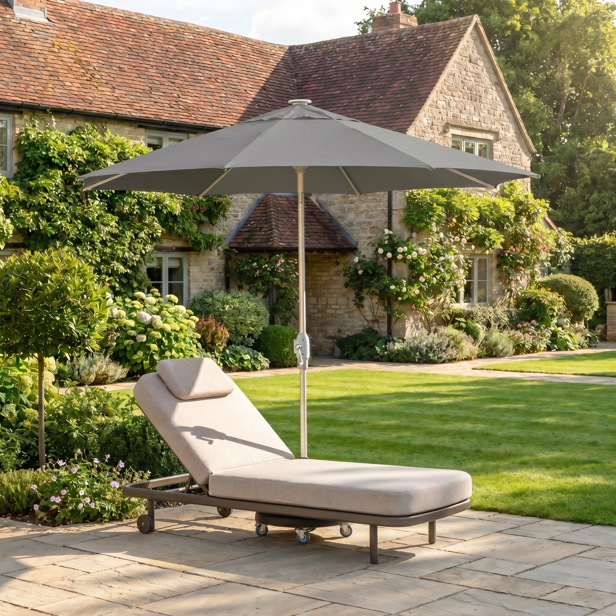 Grey Zelos 2.5M Round Parasol with LED Lighting shading a beige lounge chair on a stone patio, in front of a stone house surrounded by greenery.