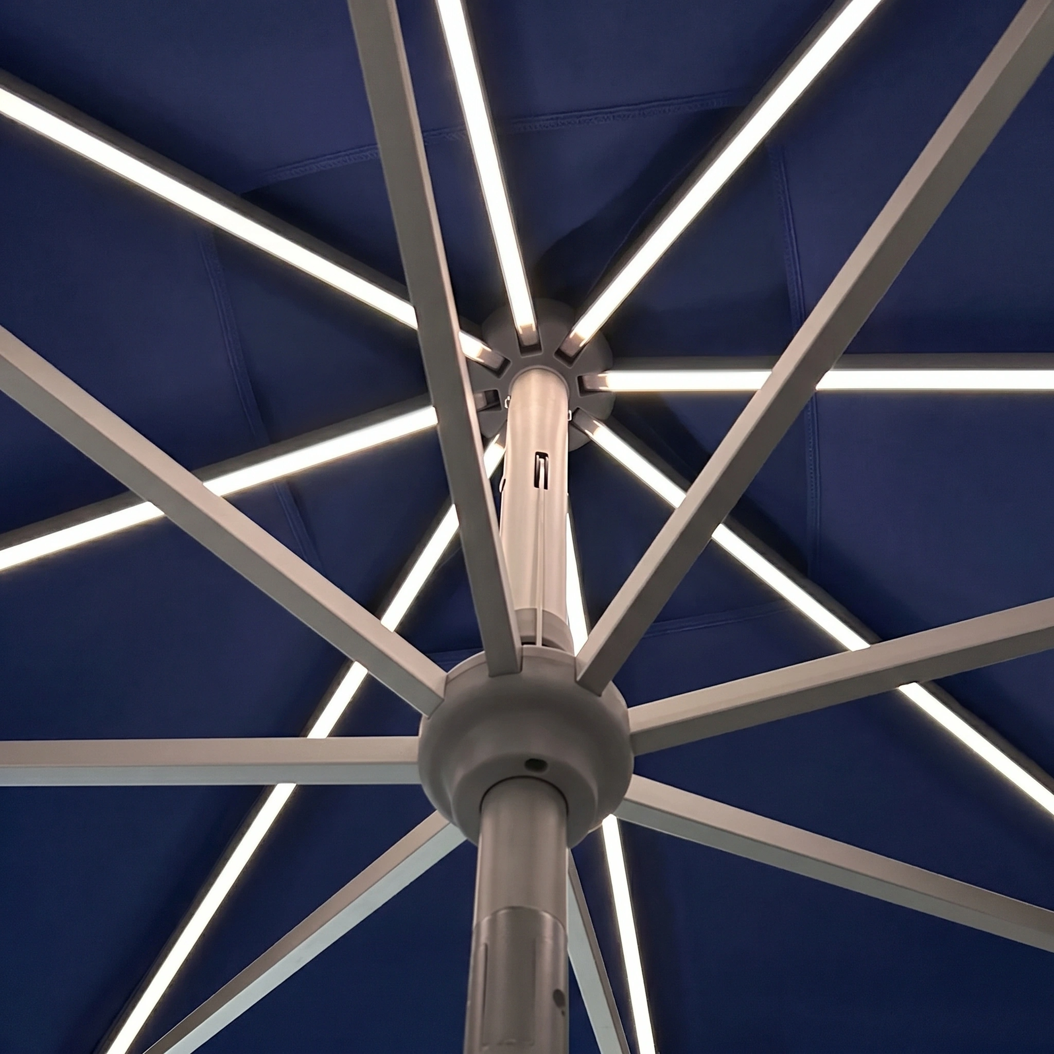 View from below of the Zelos 3m Round Parasol with LED Lighting in Navy, featuring metal ribs illuminated by integrated LEDs for a stylish glow.