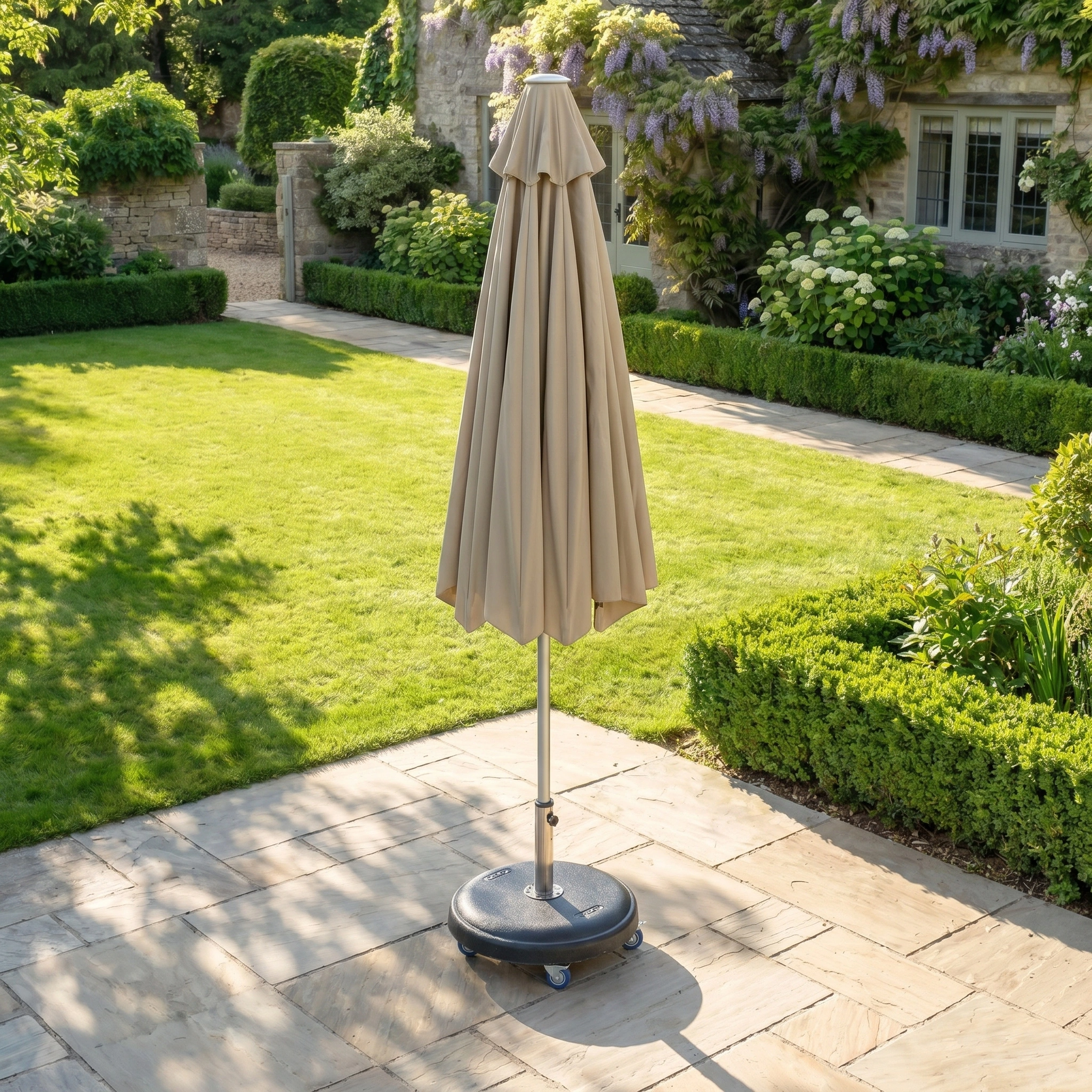 Closed taupe Zelos 2.5M round parasol with LED lighting, set on a wheeled base for easy movement across the patio.