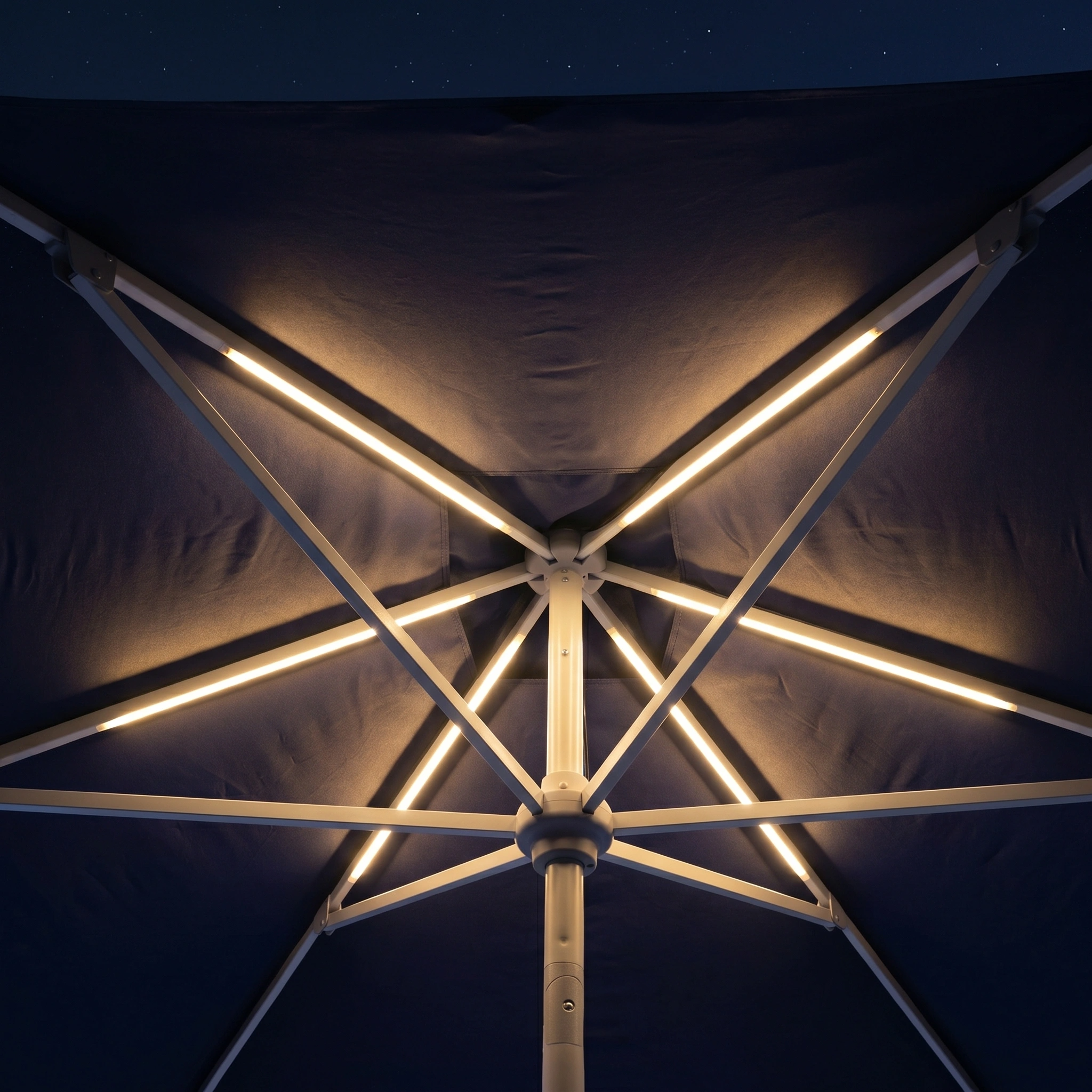 Beneath the Zelos 3m x 2m Rectangular Parasol with LED Lighting in Navy, its white-rib LEDs glow as stars twinkle above in the night sky.