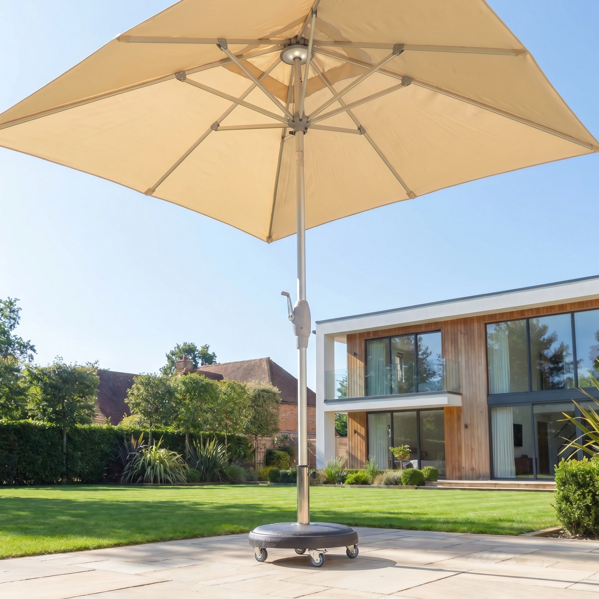 The Zelos 2.5m Square Parasol with LED Lighting in Cream stands on a paved area in a modern garden, providing UV protection with a contemporary house visible in the background.