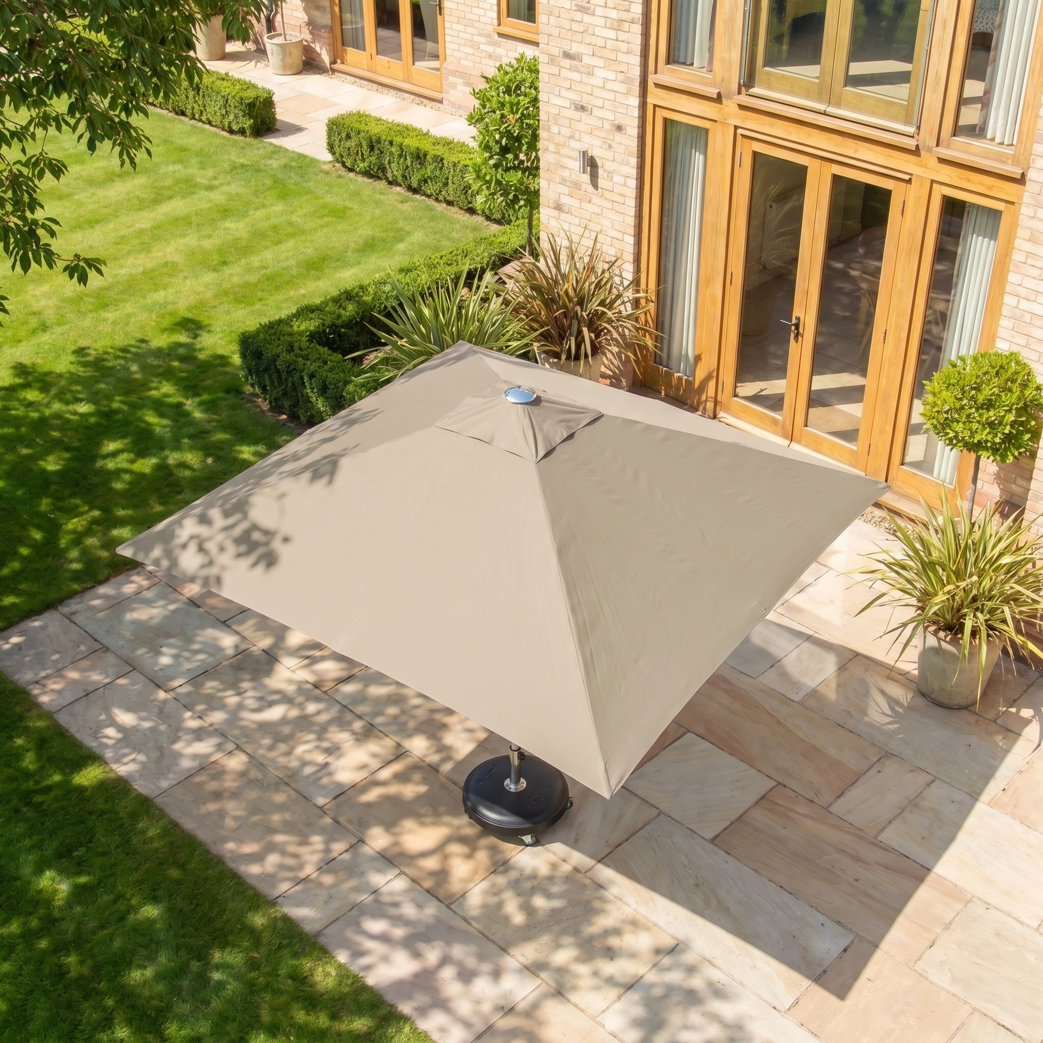 The Zelos 2.5m Square Parasol with LED Lighting in Taupe delivers stylish UV protection for your patio or garden, featuring a modern design perfect beside brick houses and large windows, while enhancing outdoor living with integrated lighting.