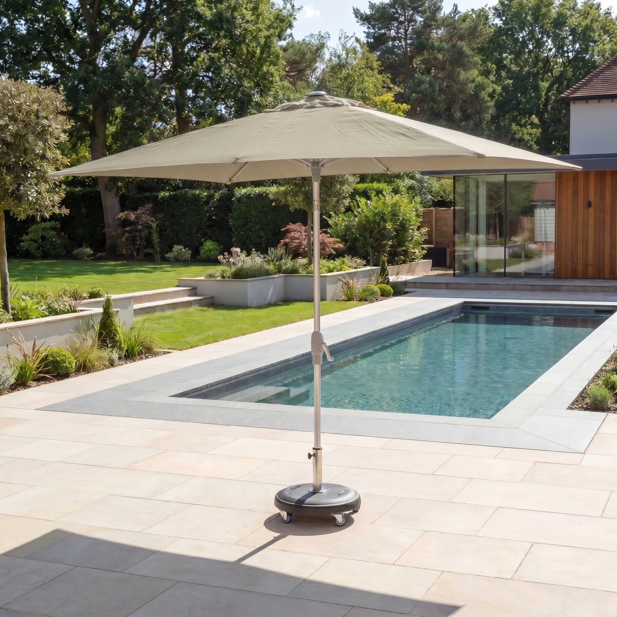 The Zelos 3m x 2m Rectangular Parasol with LED Lighting in Taupe stands beside a modern backyard pool, surrounded by lush greenery and a contemporary house.