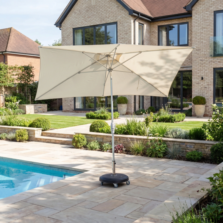 The Zelos 3m x 2m Rectangular Parasol with LED Lighting in Cream stands beside a swimming pool in a landscaped backyard, providing stylish UV protection.