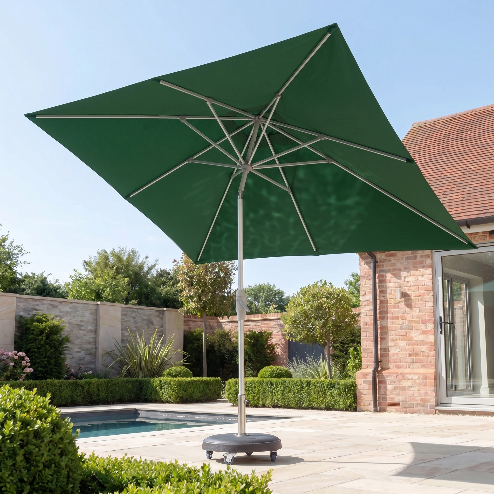 The Zelos 3m x 2m Rectangular Parasol with LED Lighting in Green offers stylish UV protection by the poolside, perfect for sunny days on your patio, with a brick house and garden in the background.
