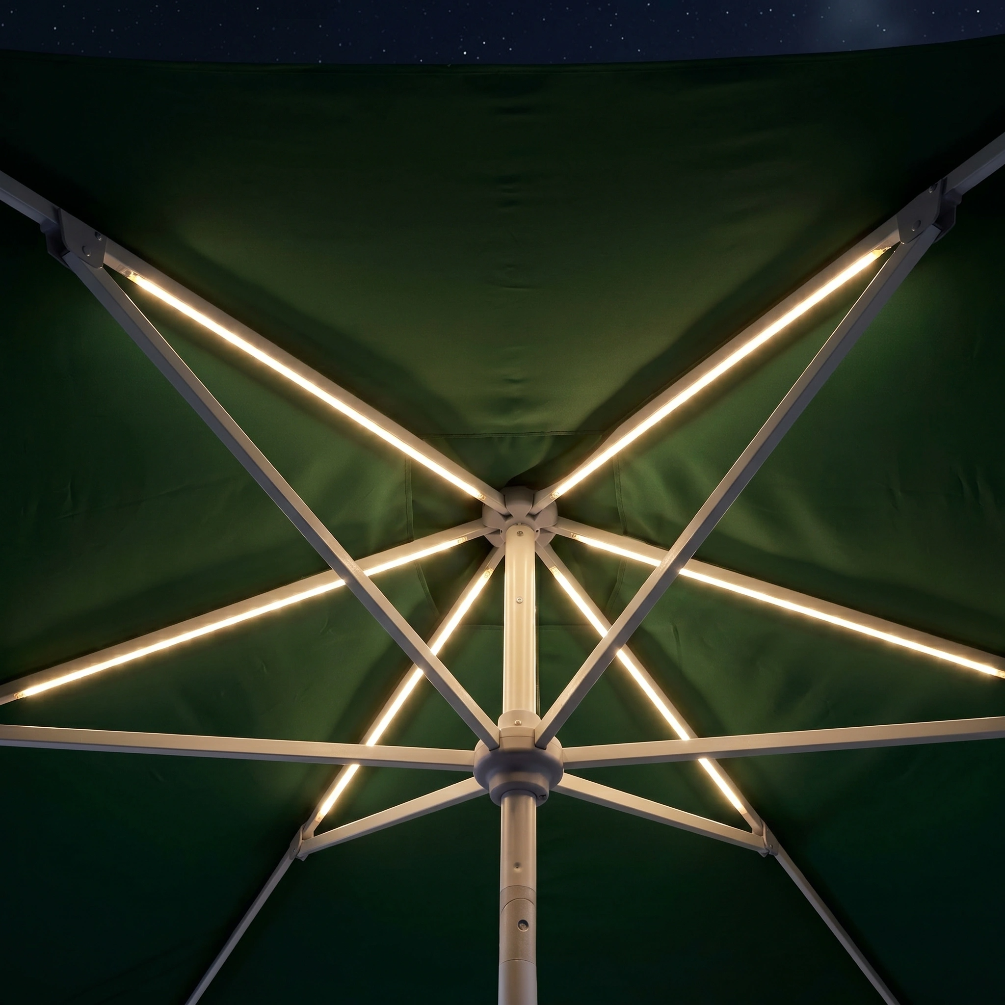 View from beneath the Zelos 3m x 2m Rectangular Parasol with LED Lighting in Green, its illuminated ribs shining against the dark night sky.
