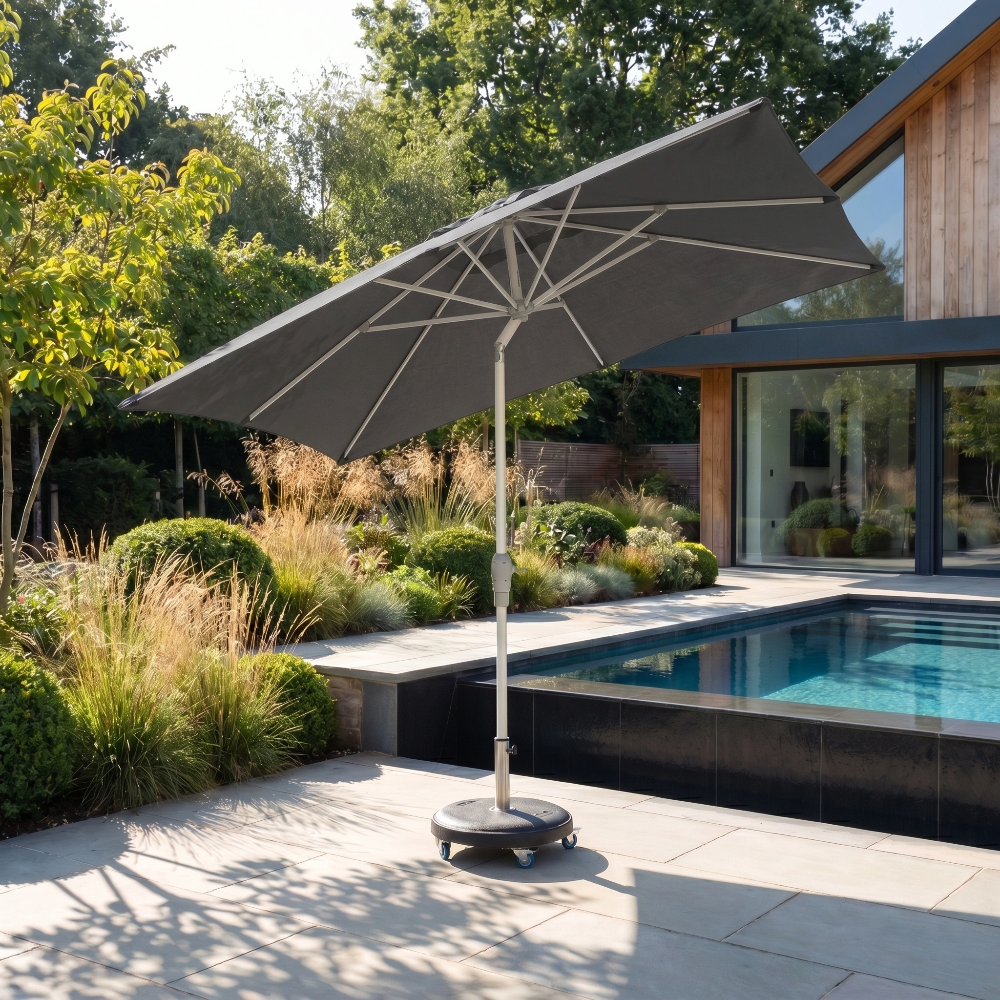 The Zelos 3m x 2m Rectangular Parasol with LED Lighting in Grey provides stylish shade and comfort for modern poolside spaces with greenery and contemporary homes.