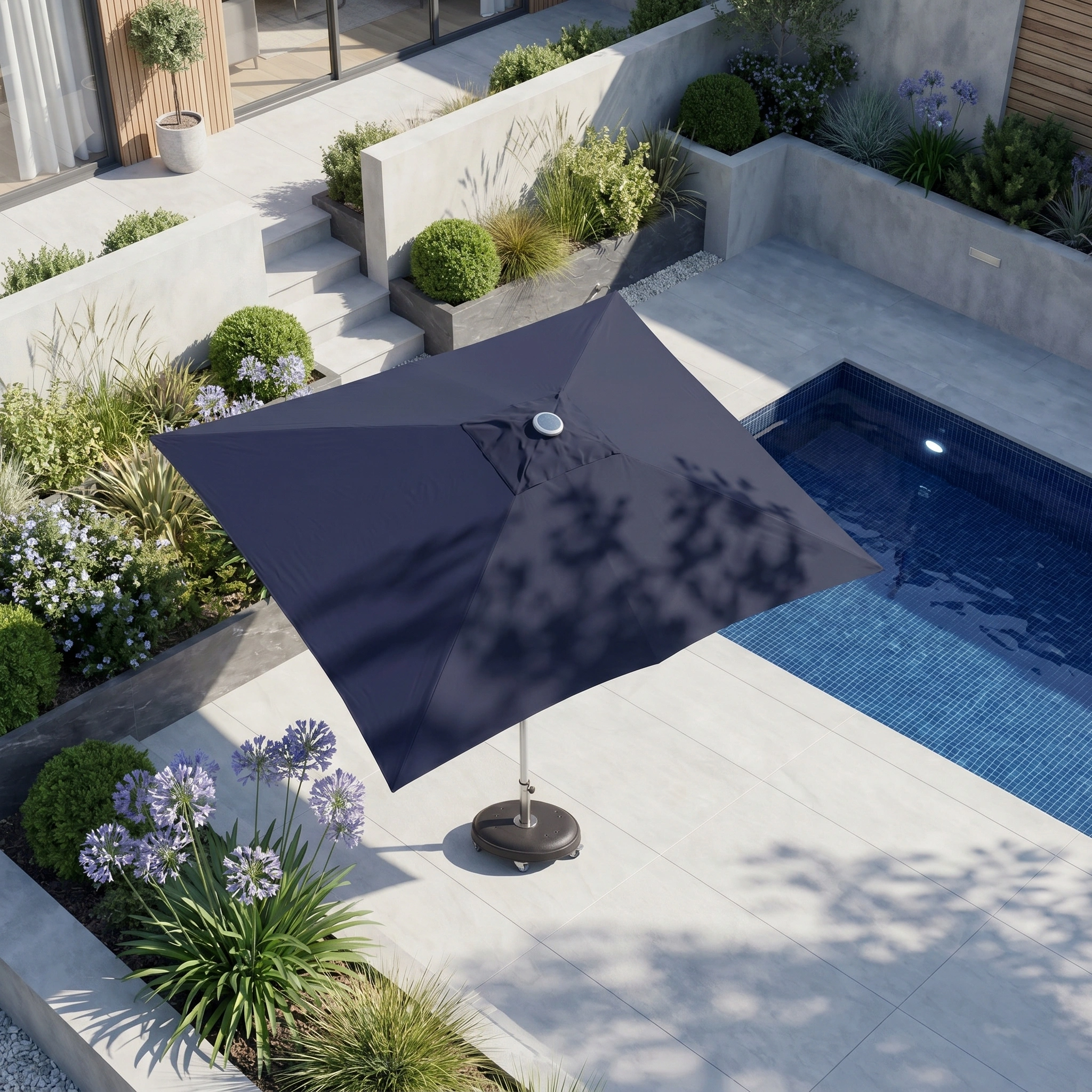The Zelos 3m x 2m Rectangular Parasol with LED Lighting in Navy shades a modern poolside patio, surrounded by plants and minimalist landscaping.