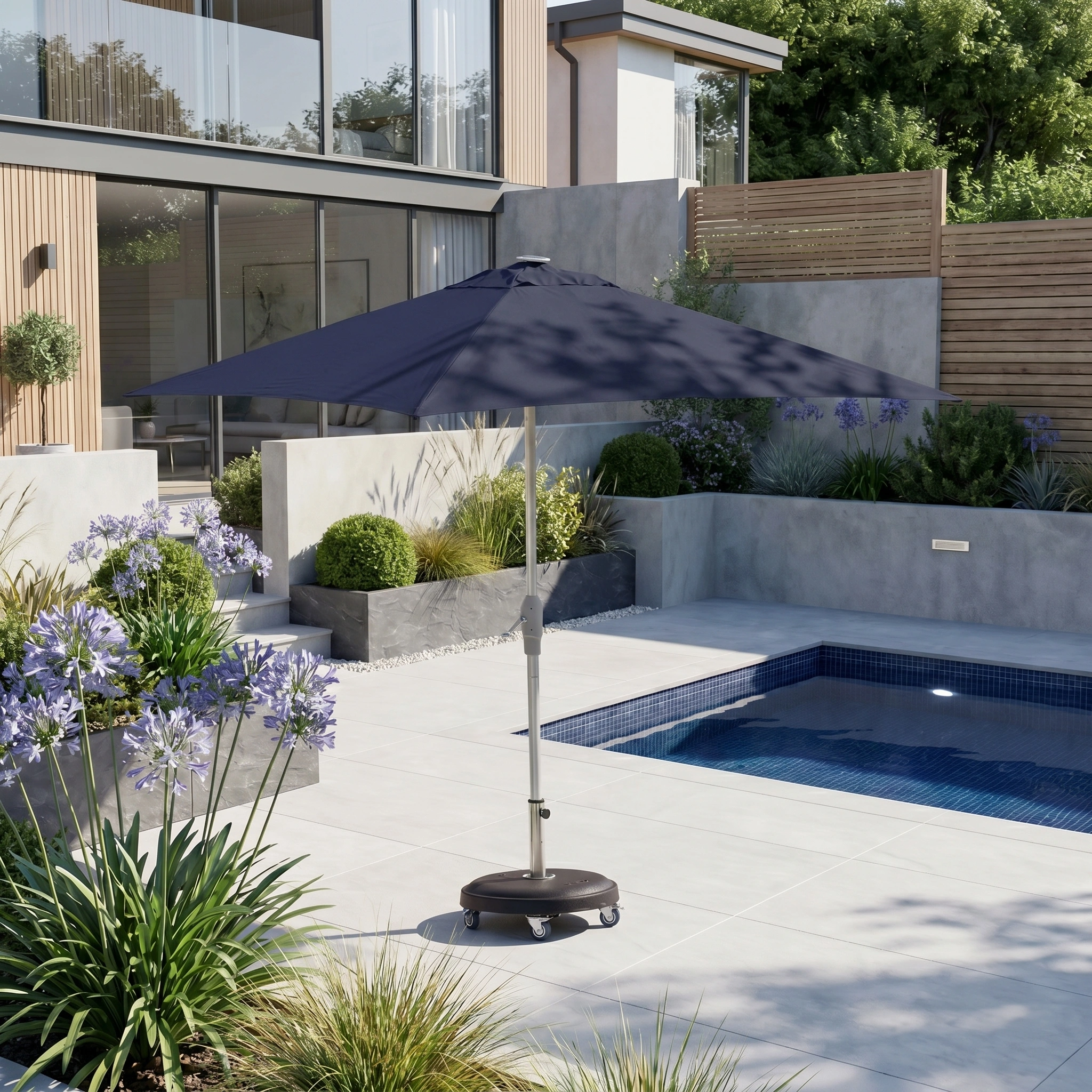 The Zelos 3m x 2m Rectangular Parasol with LED Lighting in Navy stands by a pool in a modern backyard with lush plants, adding style and UV protection.