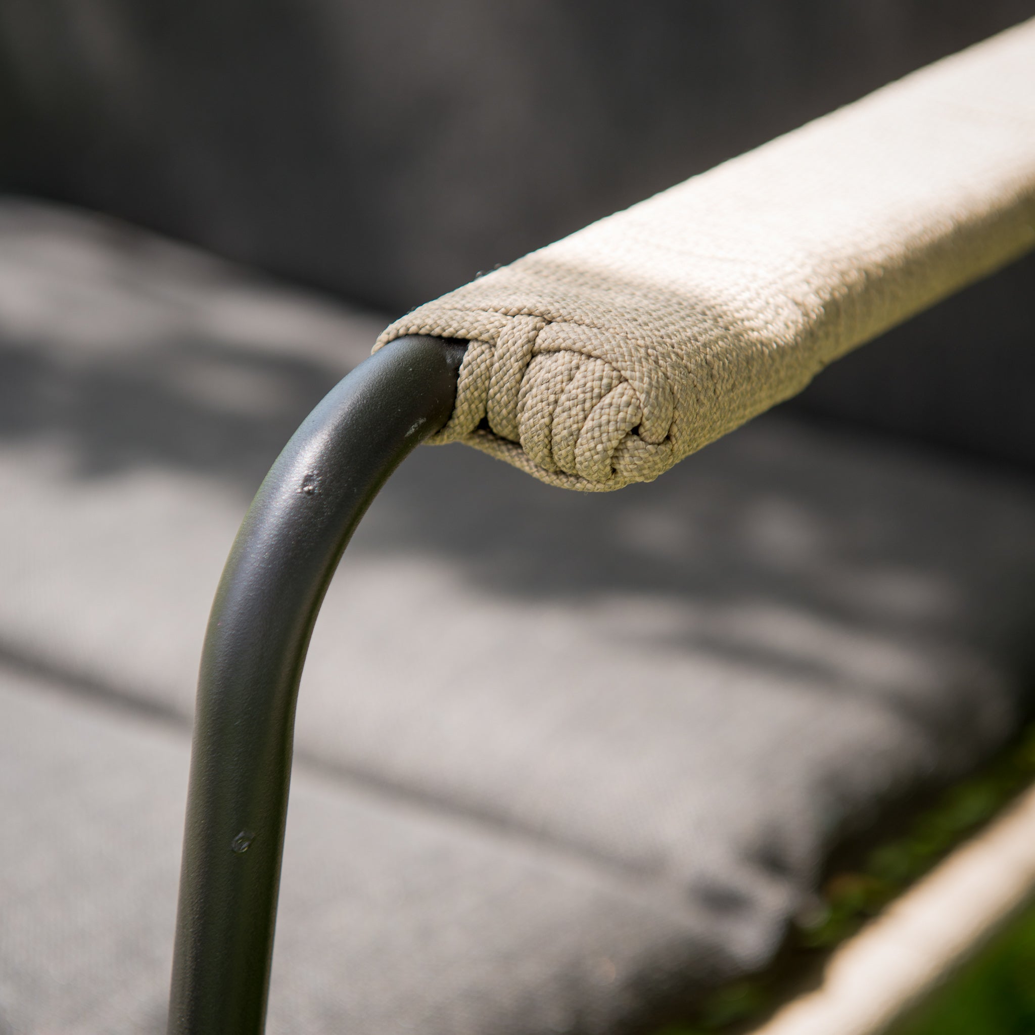Close-up of a patio chair armrest from the Scandic 2 Seat Round Lounge Set, showcasing beige textured fabric and a sleek black metal frame—ideal for elevating your garden furniture.