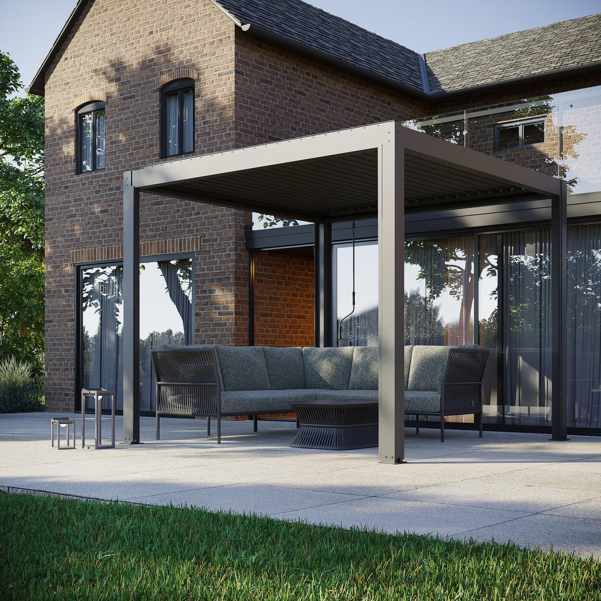 Brick house with glass doors and a modern PergoSTET Plus pergola offering a louvered roof on the patio, complete with outdoor seating and small table, featuring three drop sides and LED lighting in grey.