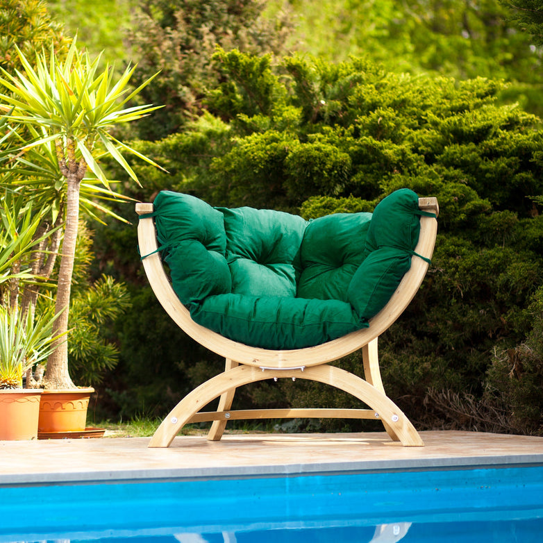 The Globo Siena Uno Seat Weatherproof in Verde Green, featuring a washable cushion and sustainable wood frame, sits by the pool amid lush greenery.