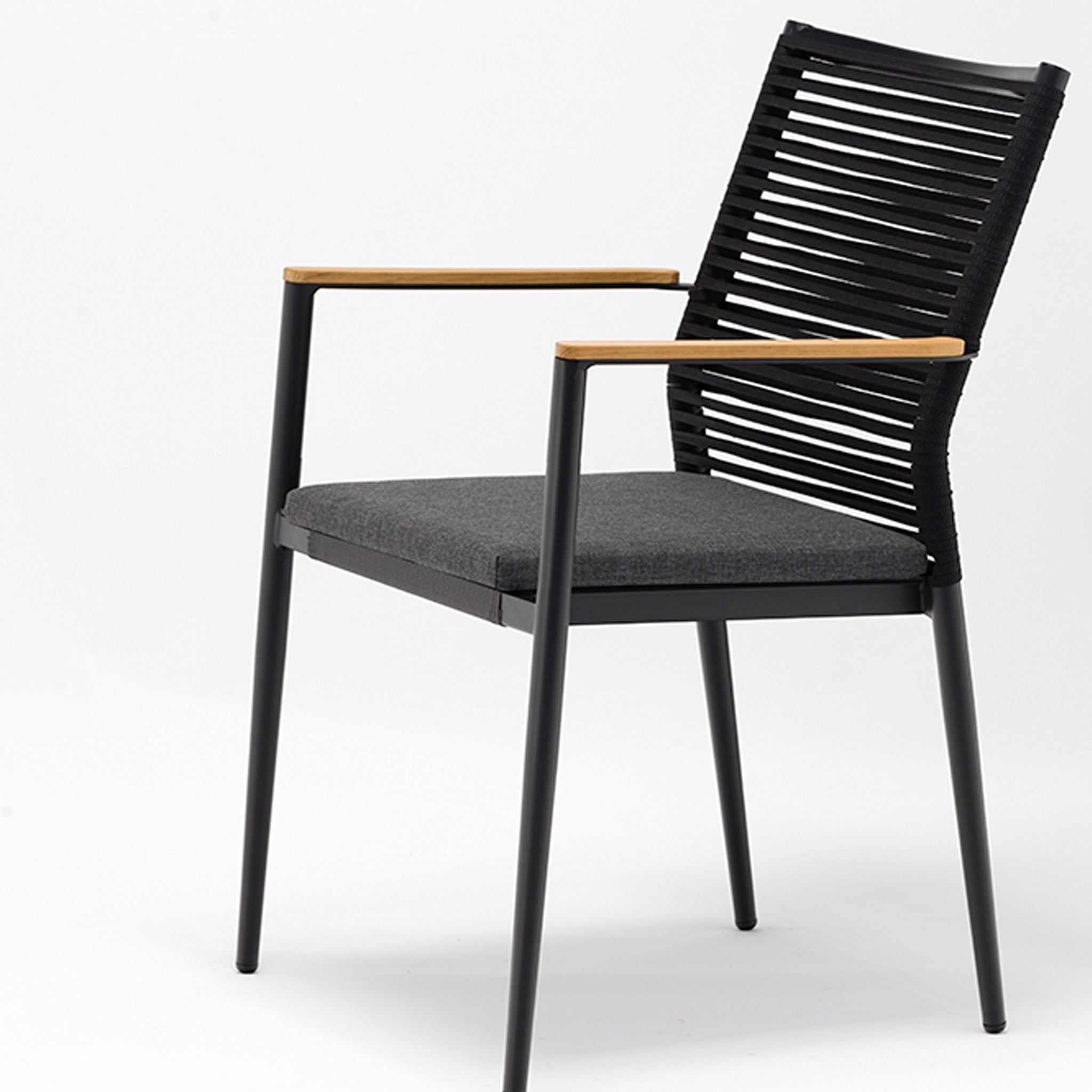 The Portland 4 Seat Round Dining Set, featuring a teak table in charcoal and modern black chairs with cushioned seats, wooden armrests, and slatted backrests, is set against a white background—making it the perfect addition to your outdoor dining area.