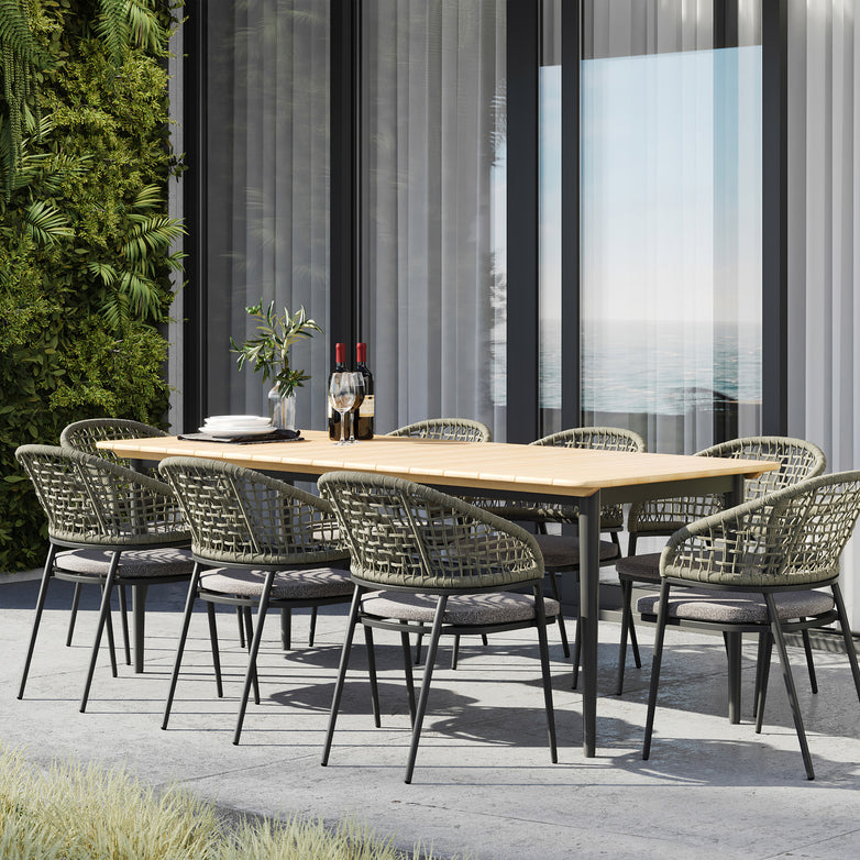 The Kalama 8 Seat Rectangular Dining Set with Teak Table in Olive Green, stylishly set on a patio, features eight wicker chairs accompanied by wine bottles, wine glasses, and plates. This weatherproof garden furniture is perfect for gatherings and durable through all seasons.