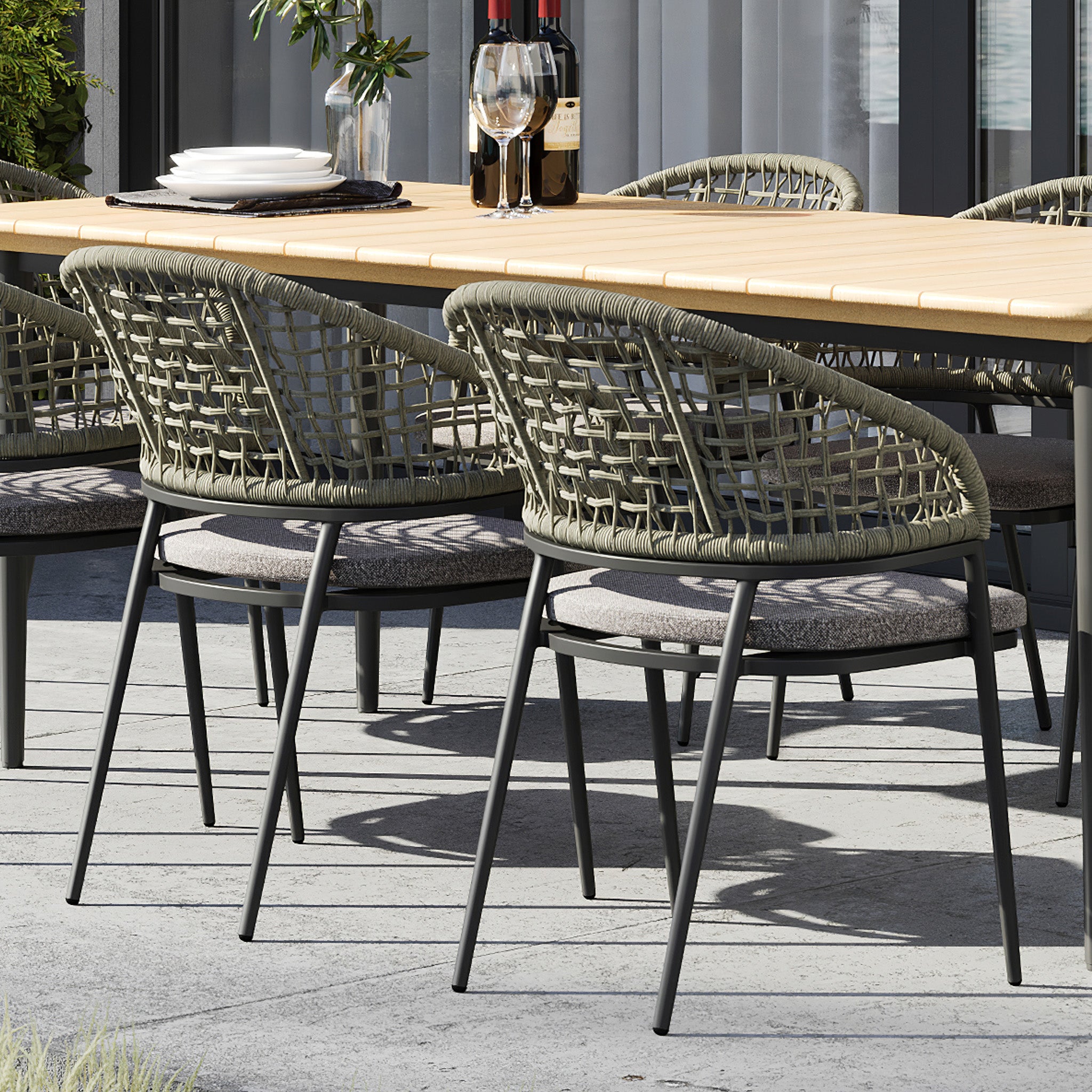 Kalama 6 Seat Rectangular Dining Set with Teak Table in Olive Green, featuring woven chairs and a sturdy teak table, elegantly set with wine glasses and bottles on a patio.