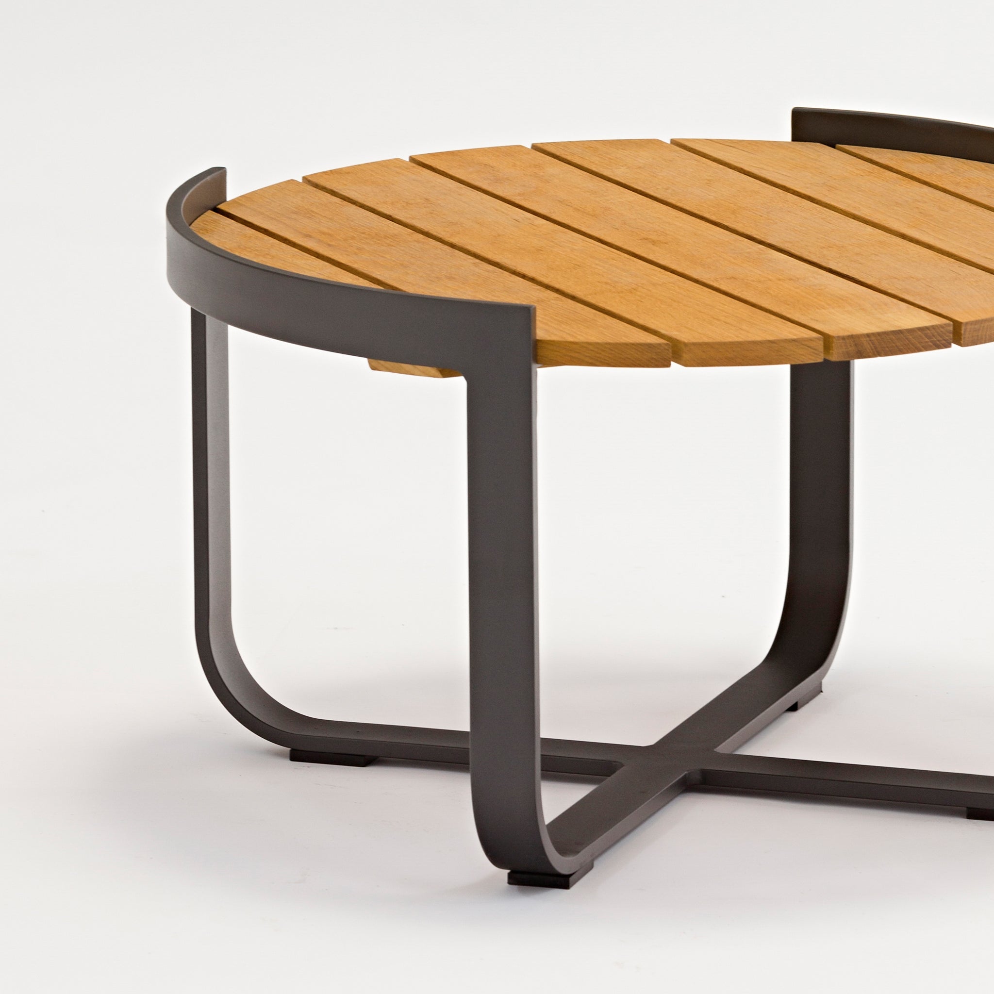 The Bloom Coffee Table with Teak Top in Charcoal is a round wooden table featuring a durable metal base and an elegant teak top, making it perfect for outdoor furniture.