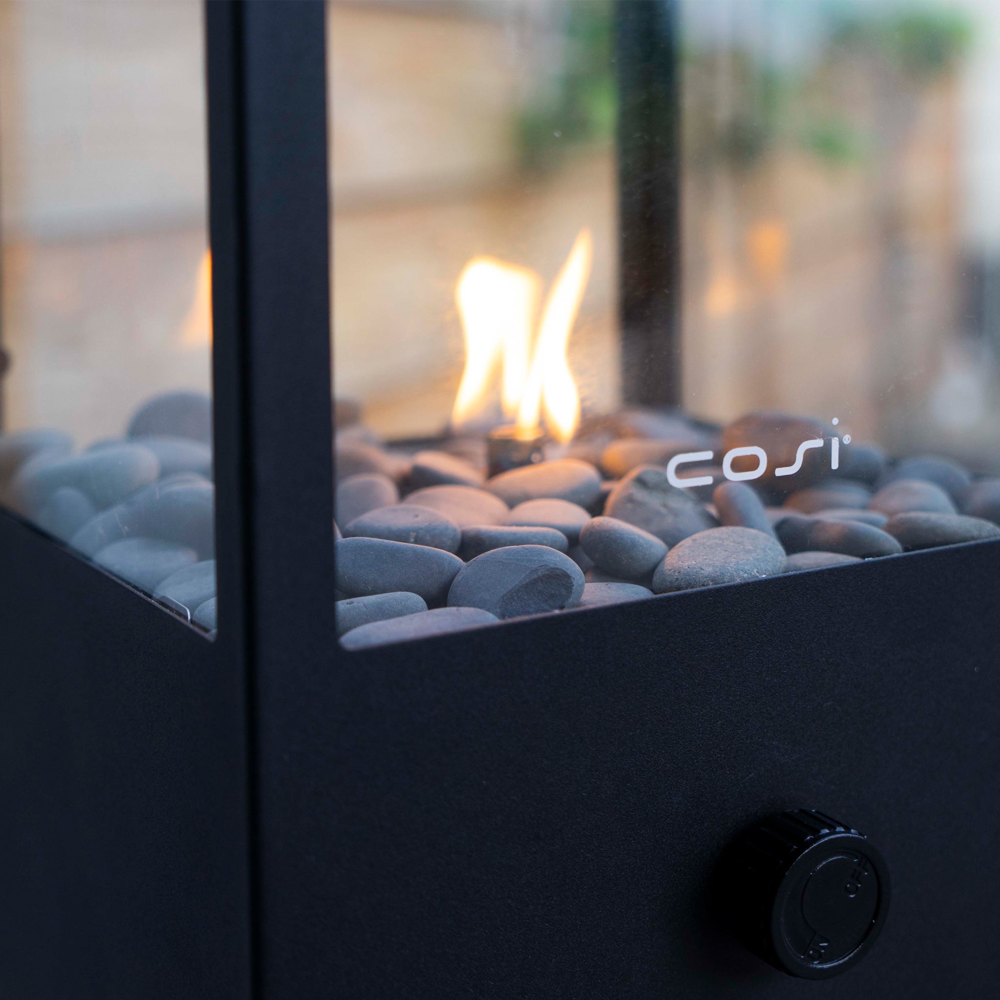 Close-up of the Cosi - Cosidome High Black Fire Lantern, showcasing visible flames and stones inside a glass enclosure with a minimalistic design resembling a stylish lantern.