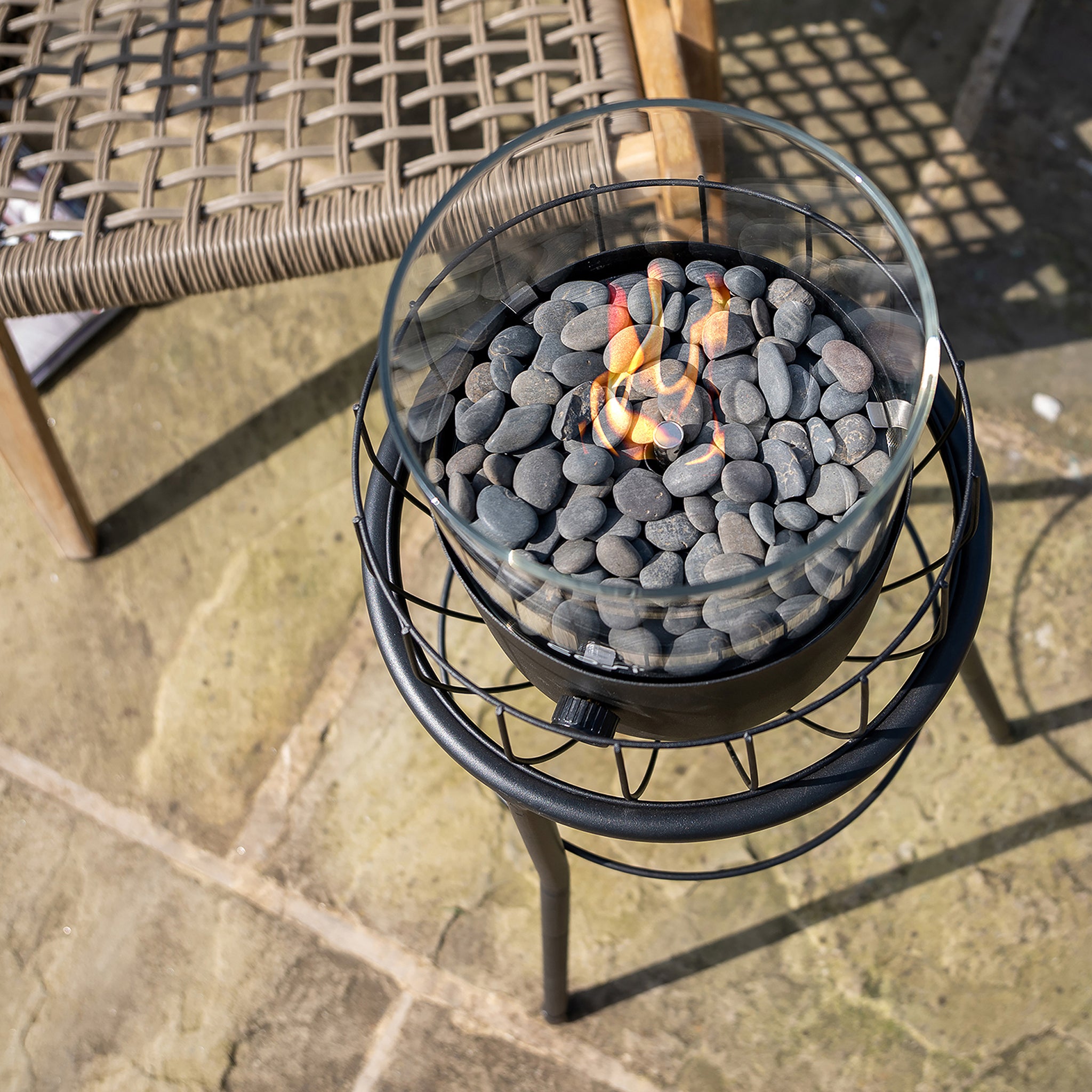 Create a chic outdoor setting with the glass fire pit's flickering flames illuminating the patio. Paired with a wicker chair, this stylish setup is enhanced by the Cosi - Cosiscoop Basket High Black Lantern for a warm and inviting ambiance.