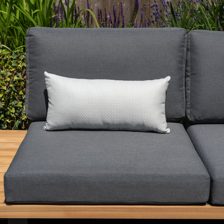 Acrisol Helix Gris Claro Bolster Scatter Cushion - 60cm x 30cm with a white rectangular accent pillow in a garden setting.