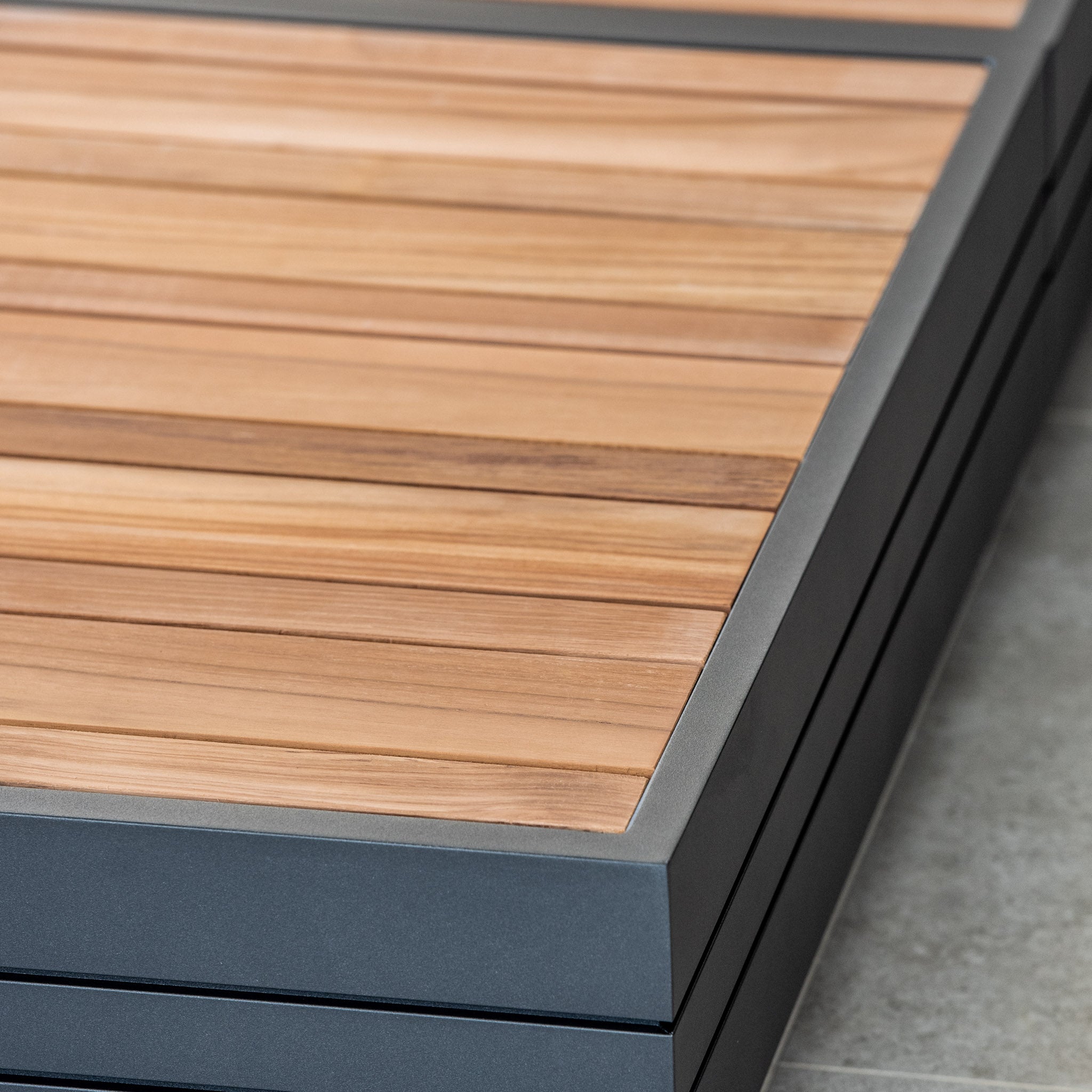 Close-up of stacked teak wooden panels with metal frames, placed on a tiled surface, reminiscent of the luxury Panama Teak Coffee Table.