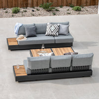 Outdoor seating arrangement featuring the Panama 3 Seat Sofa with Sun Lounger Feature in Washed Grey on a tiled patio, complemented by a wooden coffee table and sleek aluminum-framed loungers, creating an inviting oasis of stylish outdoor furniture.