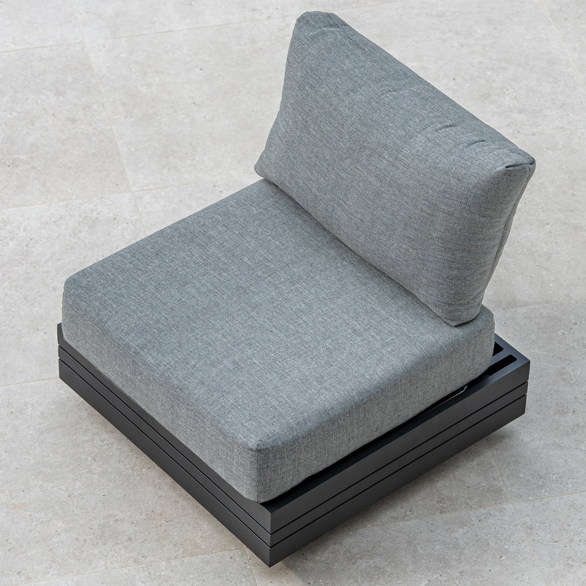 The Panama Corner Unit/Footstool in Washed Grey, featuring a sleek black metal frame and versatile modular design, sits elegantly on a light tiled floor.