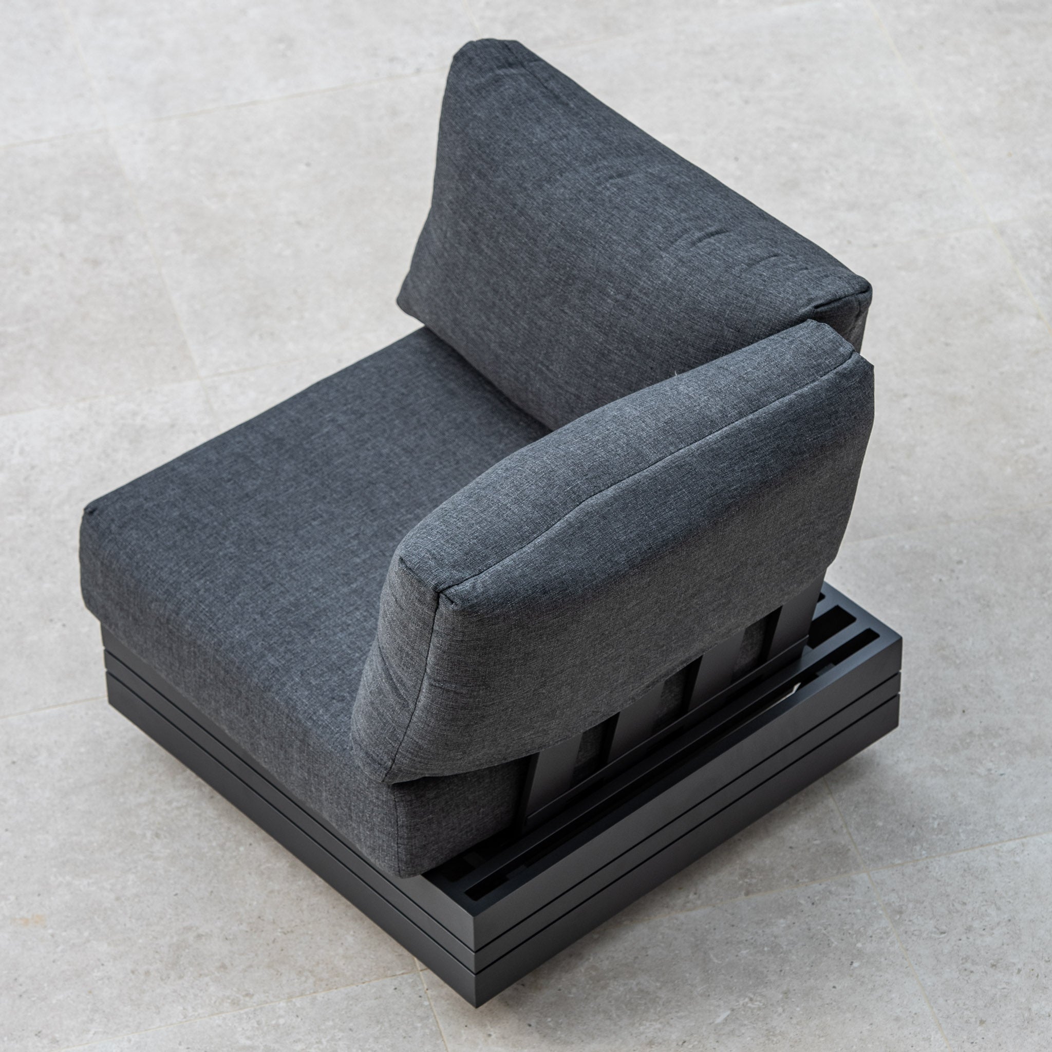 Top view of the Panama Corner Unit/Footstool in Charcoal with a metal base on a light grey tiled floor, seamlessly fitting as part of a versatile modular system.